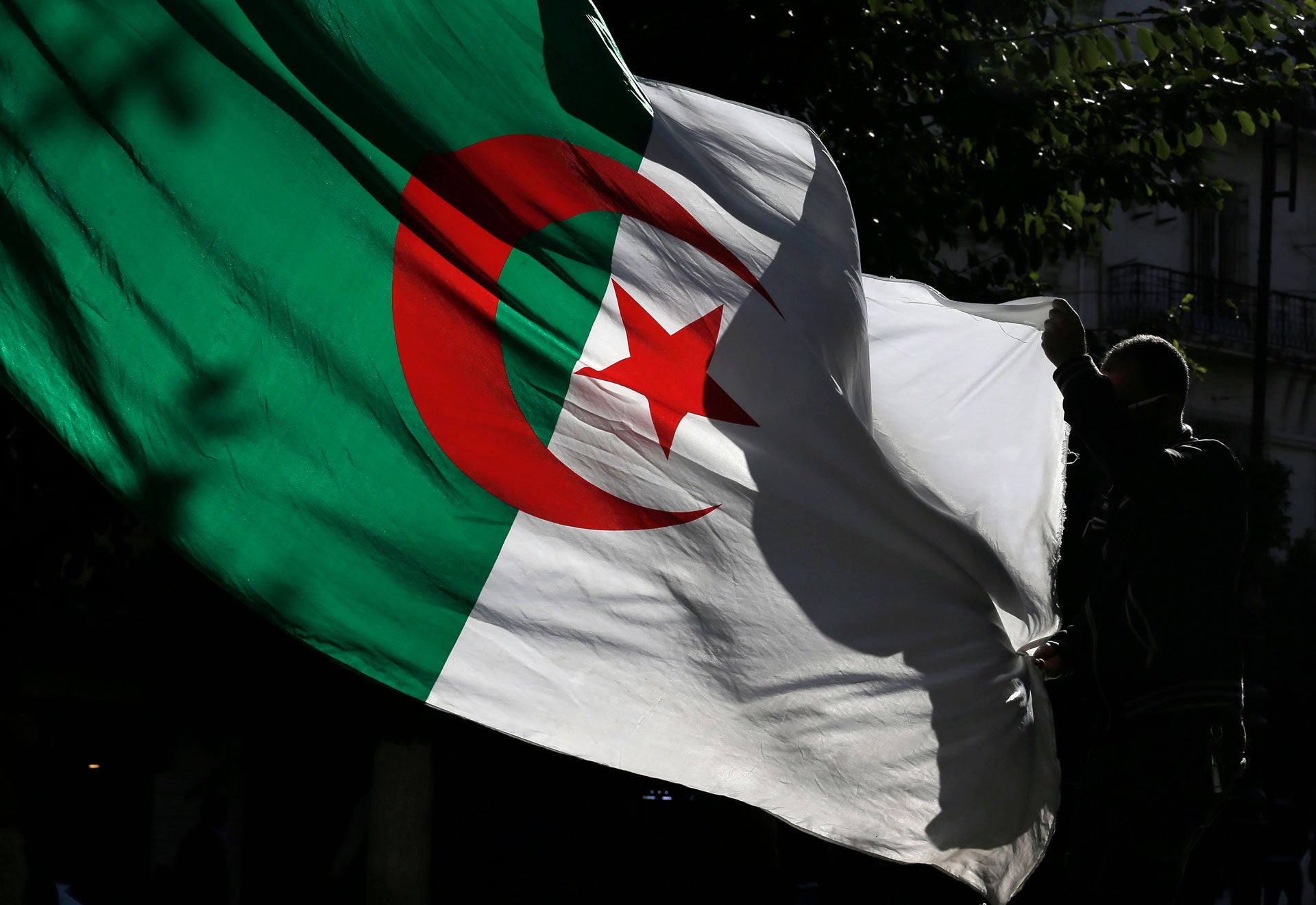 An Algerian demonstrator holds the Algerian national flag as he stage a protest against the government in Algiers, Algeria, Friday, Nov.29, 2019. 