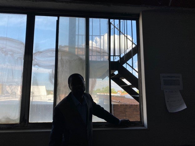 A man poses in his apartment, obscured by shadows