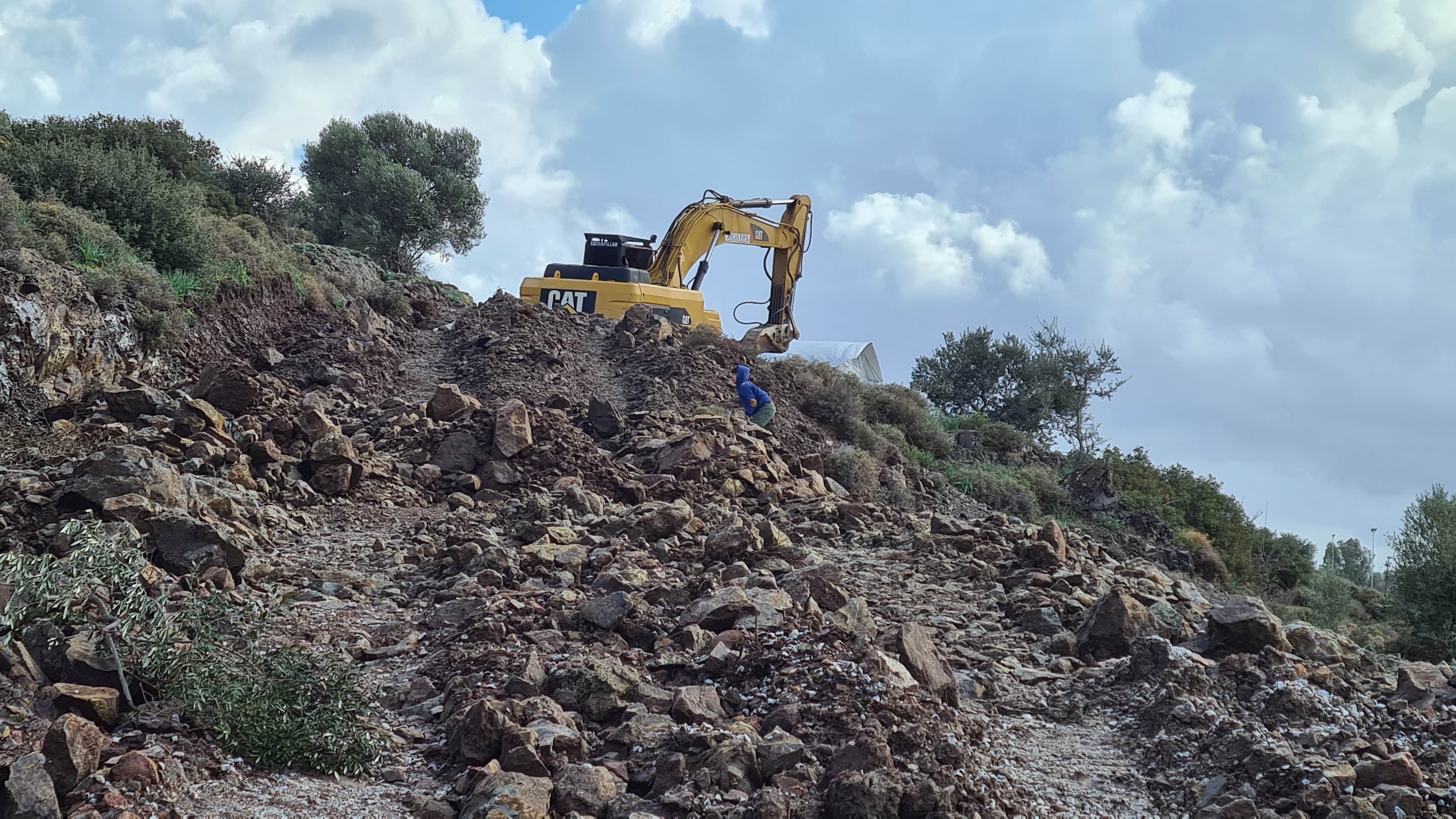 child plays next to an earth digger 