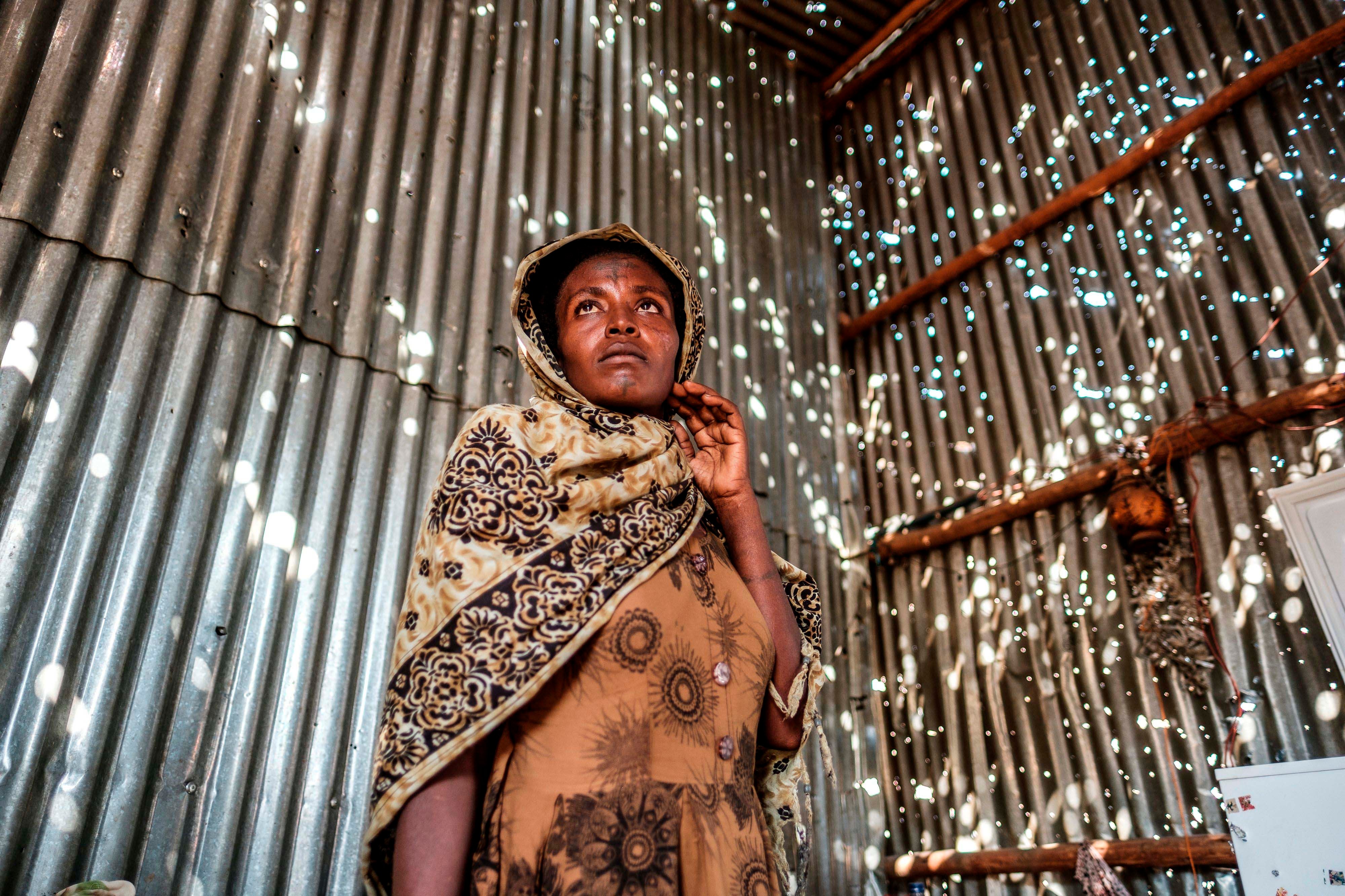 A woman stands in a metal sheet room that was damaged by shelling in Humera town, Tigray region, Ethiopia, on November 22, 2020. In that residential compound, two women and an elderly man were killed by shelling and gunfire, and two women were wounded.