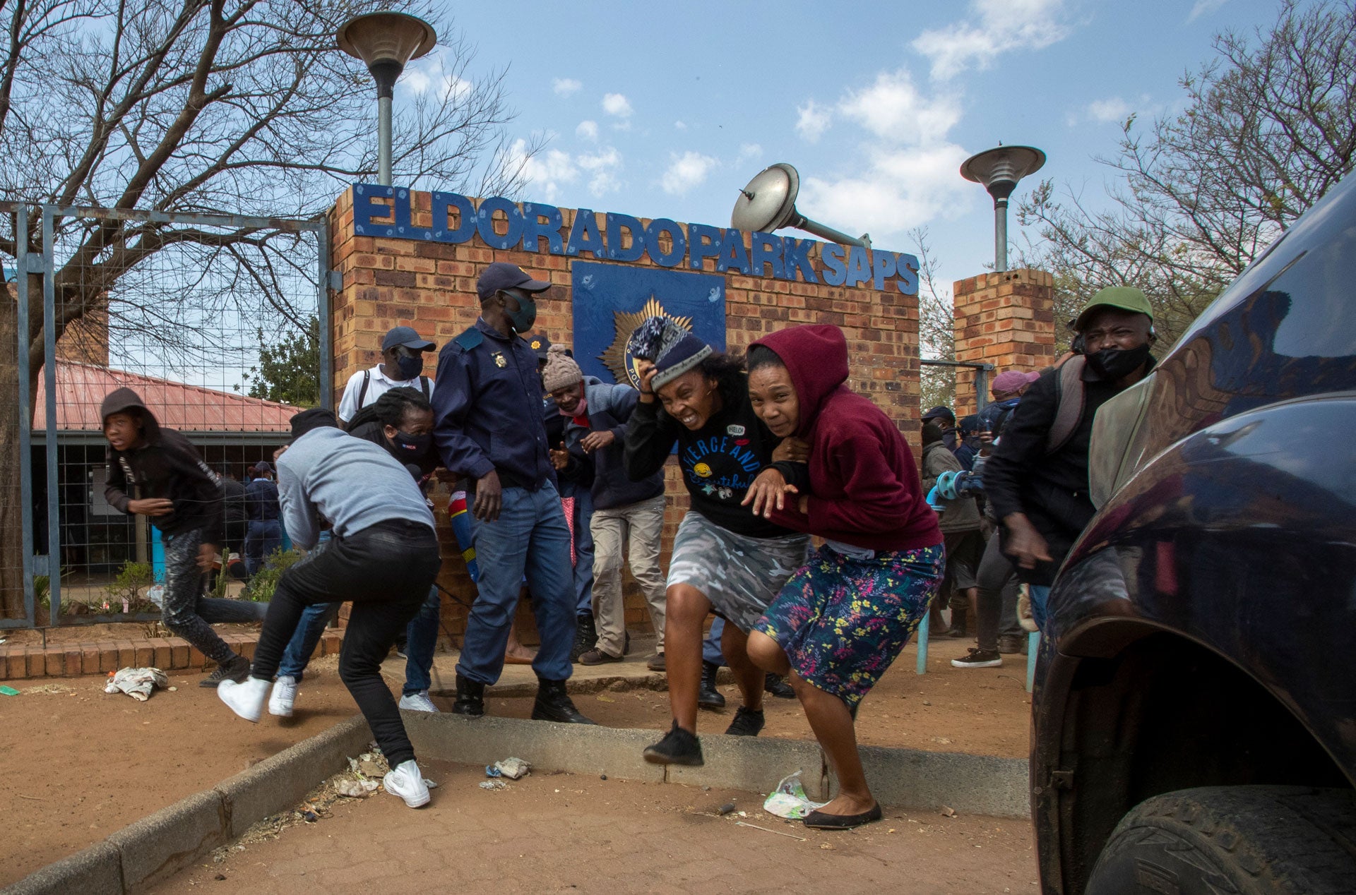 Protesters run for cover as they clash with police at Eldorado Park police station in Johannesburg, South Africa, August 27, 2020. 