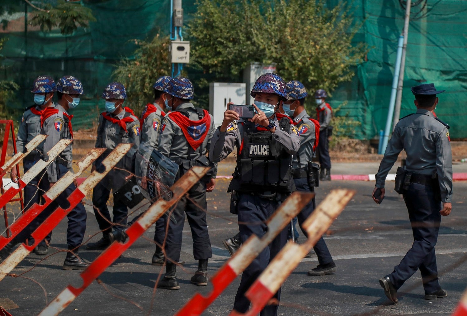 A police officer takes visuals of protesters close to the Indonesian Embassy in Yangon, Myanmar Wednesday, Feb. 24, 2021. 