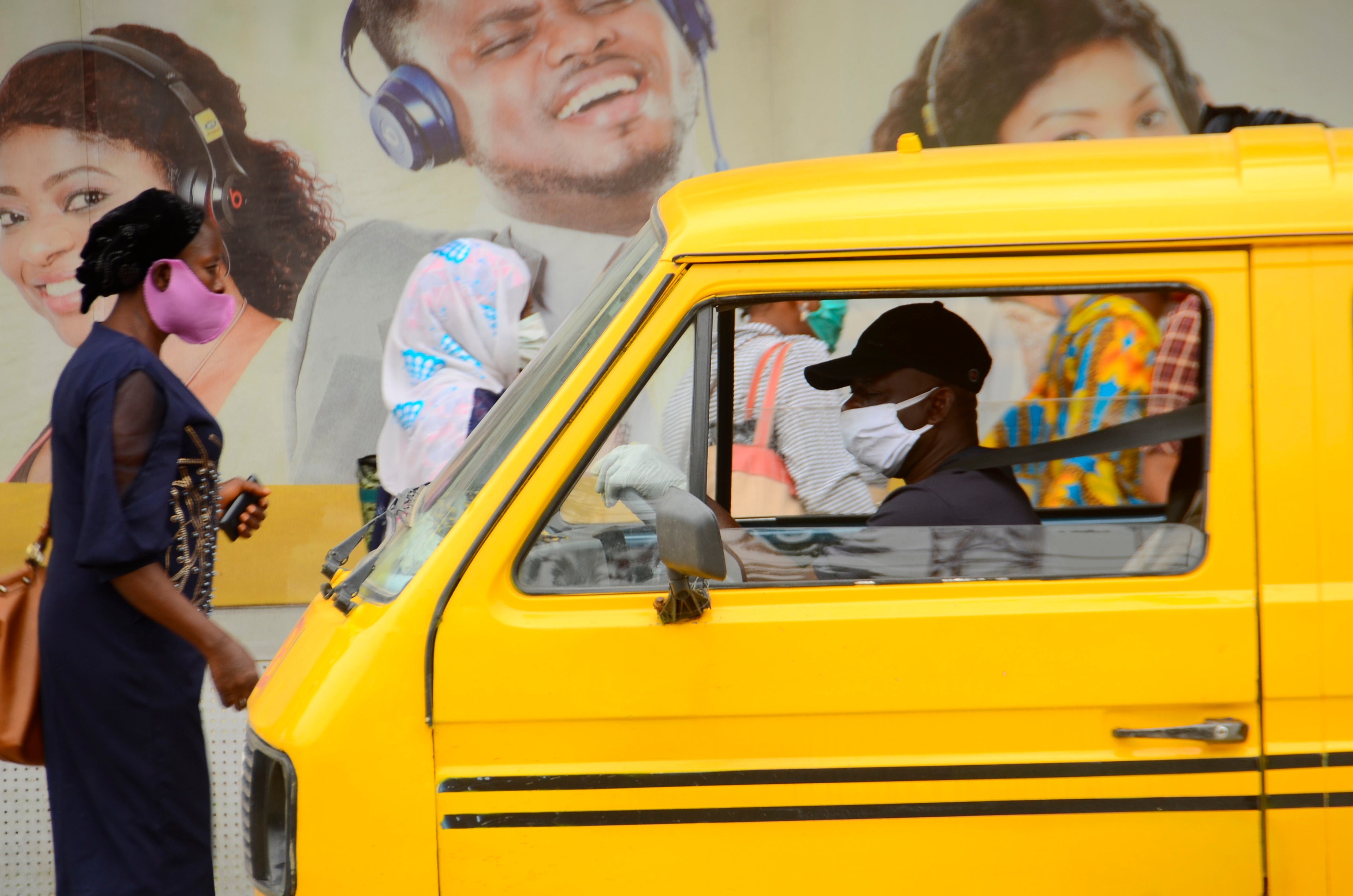 A yellow bus driver wearing a face mask