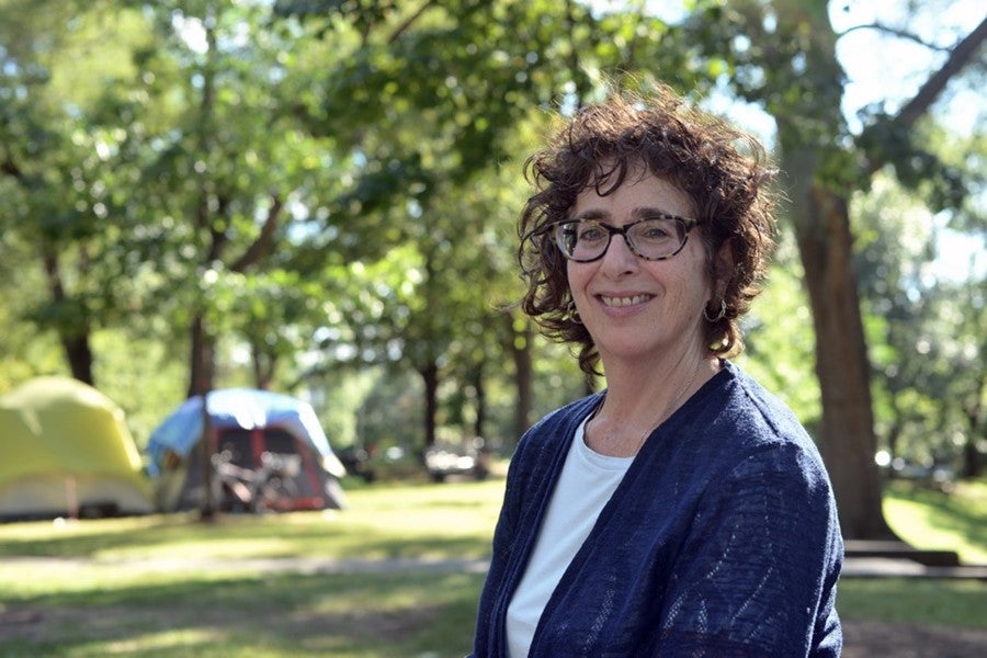 A woman stands outside during the day looking at the camera