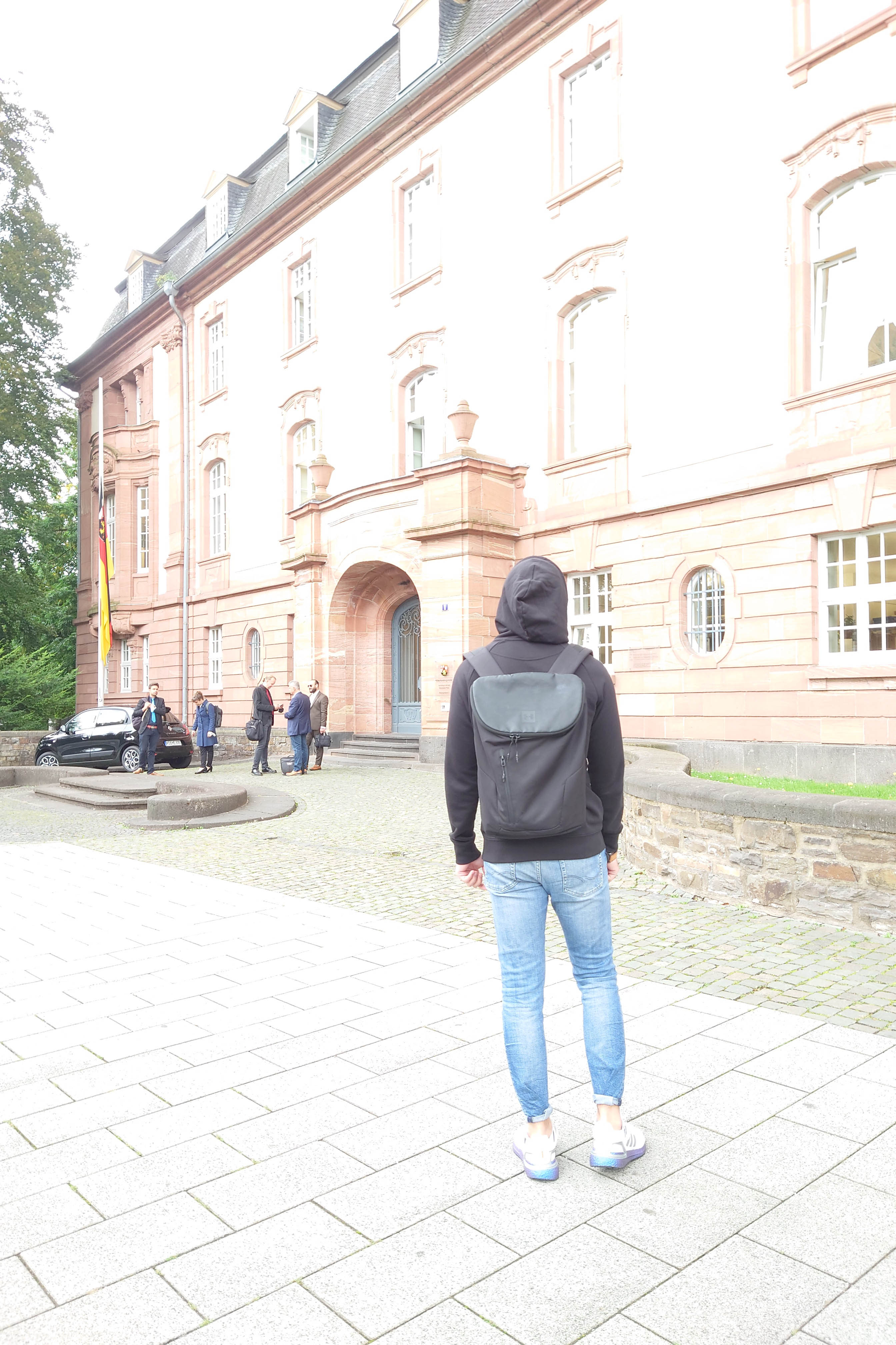 A shot from behind of a man standing in front of a large building