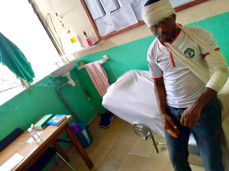 A man in a hospital room wearing bandages and a sling