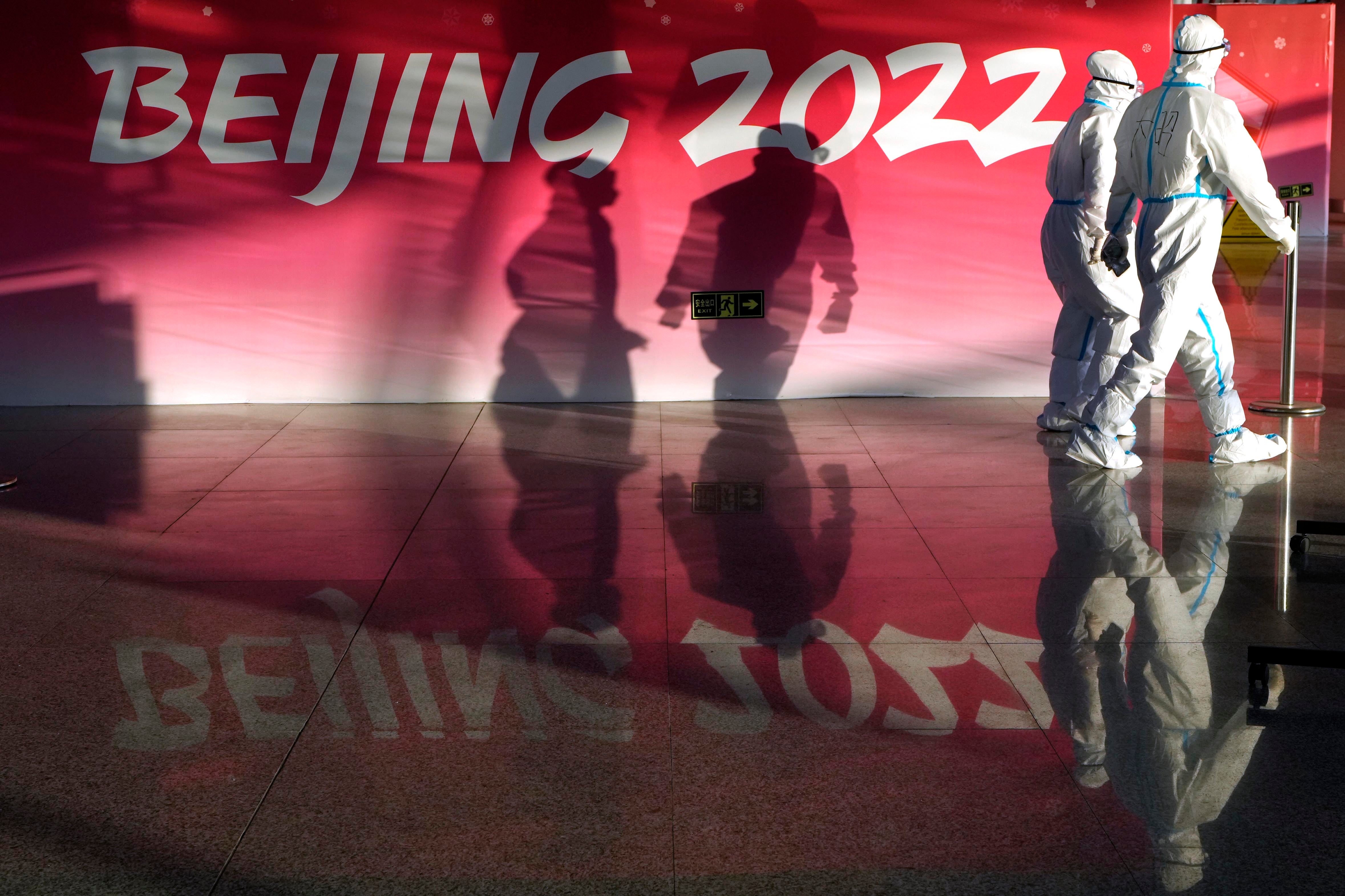 Olympic workers in protective gear walk through the Beijing Capital International Airport to assist passengers ahead of the 2022 Winter Olympics, in Beijing, January 31, 2022. 