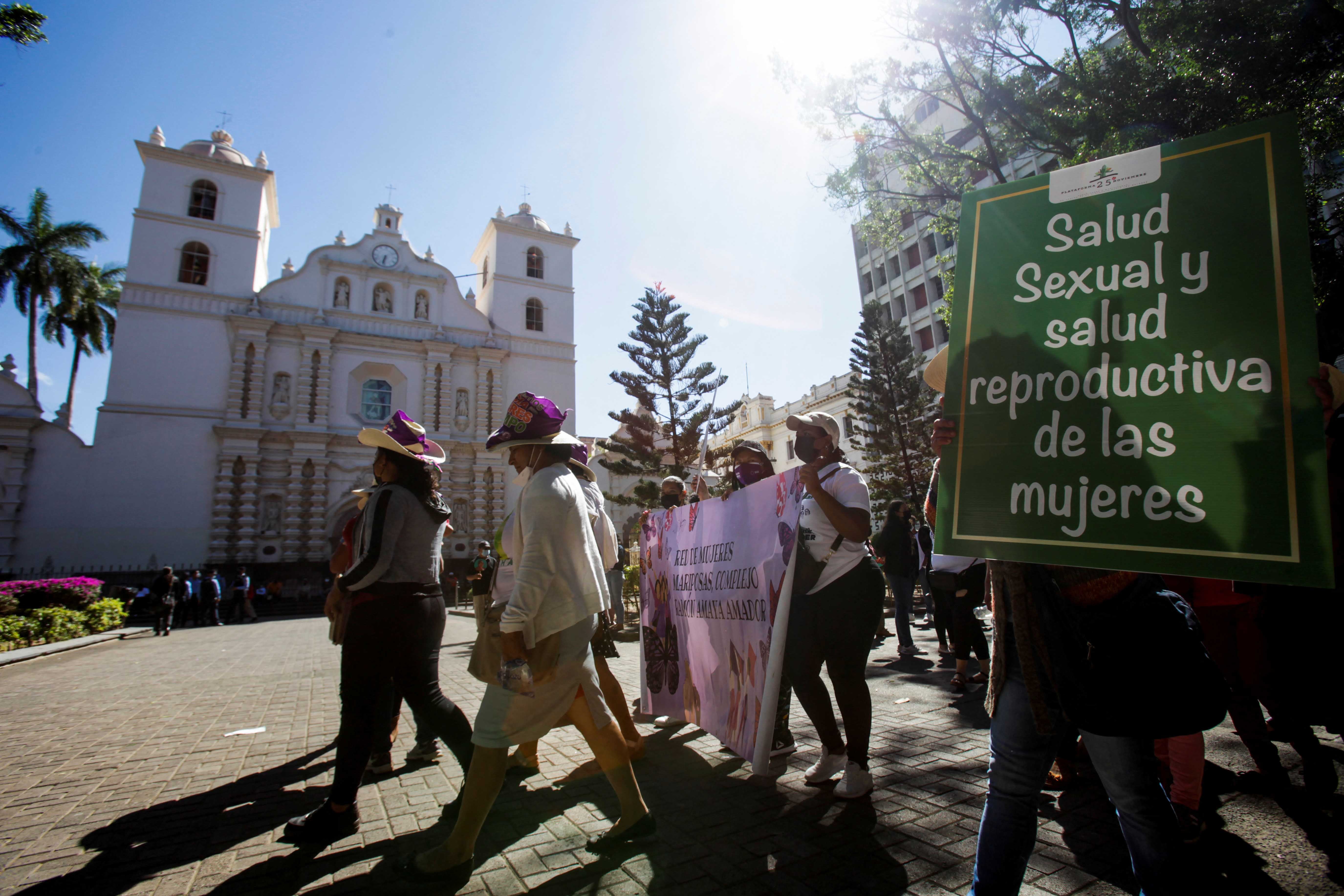 A demonstrator carries a sign reading "Women's sexual health and reproductive health" during a march to commemorate the right to vote and to celebrate the election of Honduras' first female president, in Tegucigalpa, Honduras, on January 25, 2022.