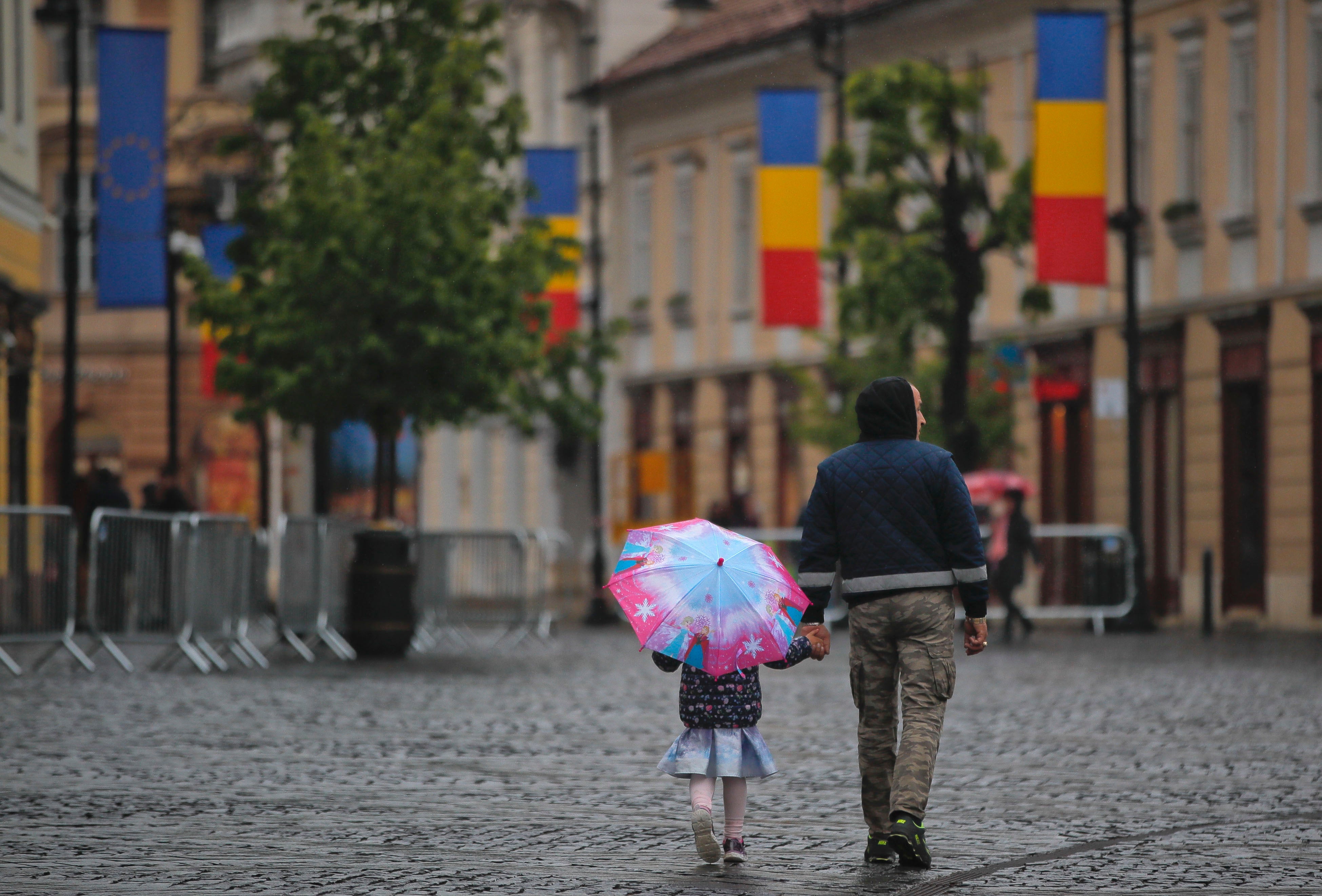 A little girl walks holding an umbrella in the Transylvanian town of Sibiu, Romania, Tuesday, May 7, 2019. (AP Photo/Vadim Ghirda)