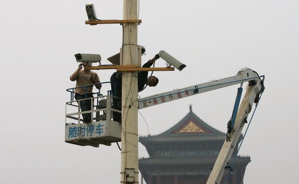Labourers adjust newly installed surveillance cameras at Tiananmen Square ahead of National Day on September 28, 2005.