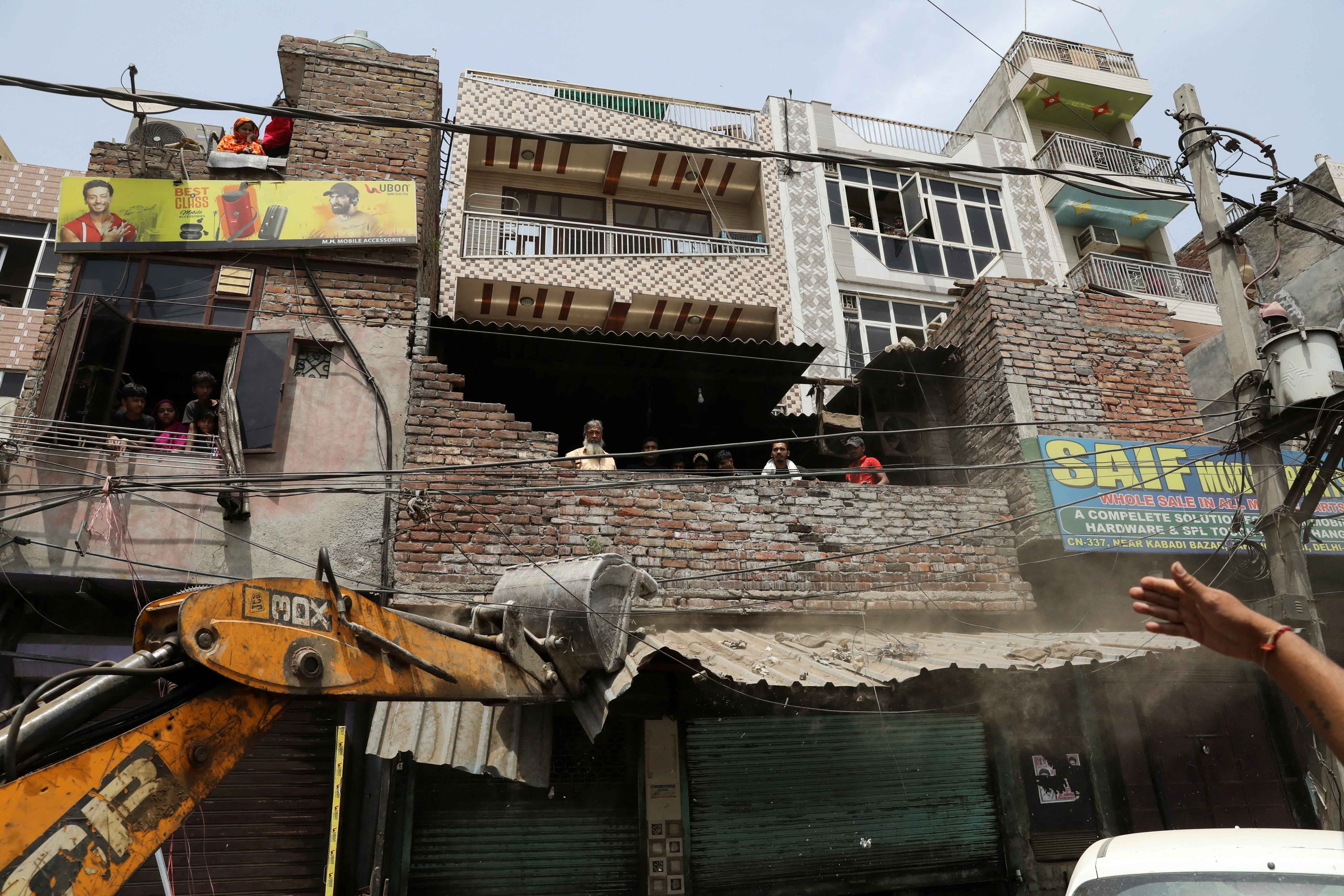 A bulldozer demolishes a shop entrance in Jahangirpuri, in New Delhi, India, April 20, 2022.