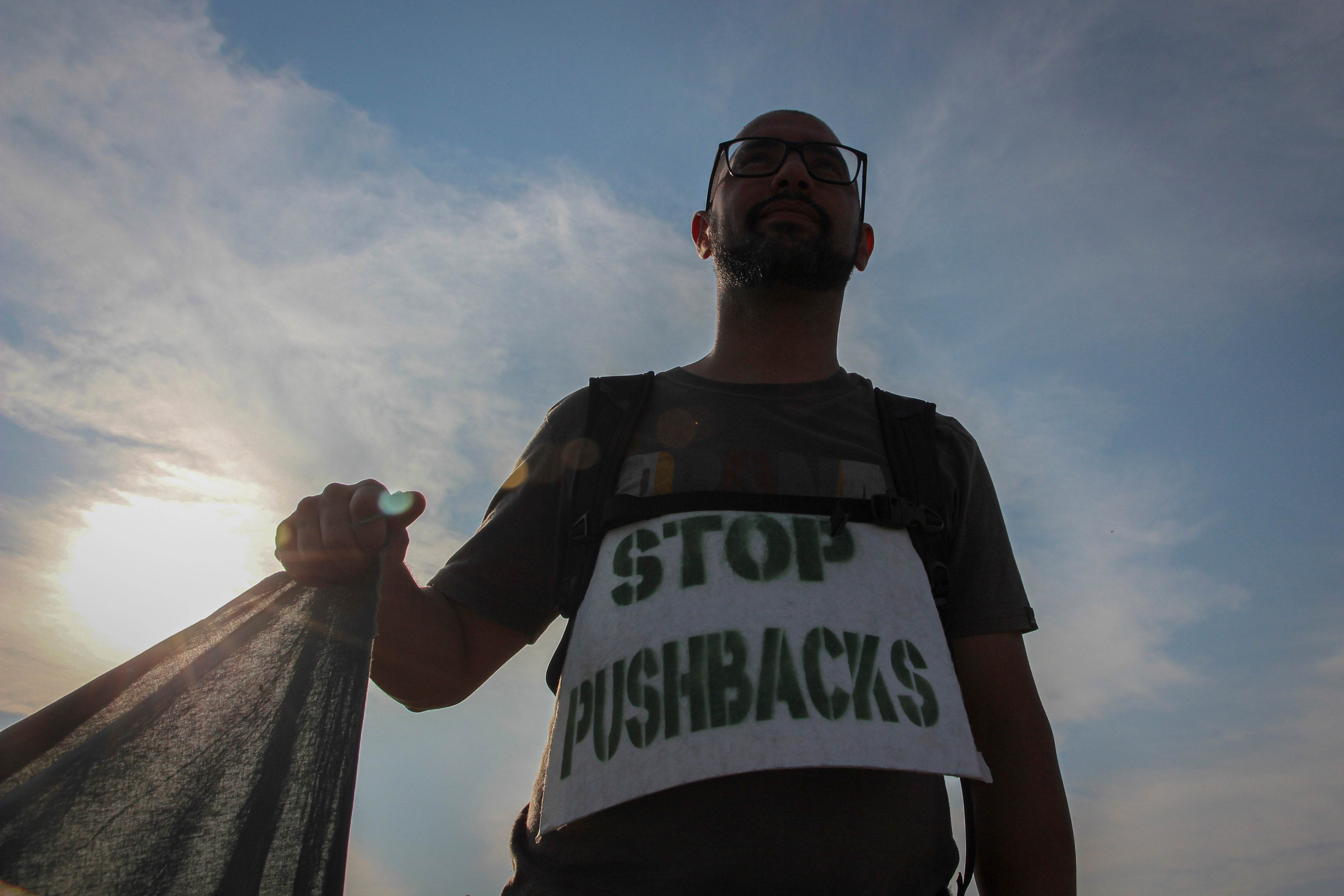 A man holds a banner during a protest against the violent pushbacks of migrants, allegedly conducted by Croatian police, near the border crossing between Croatia and Bosnia and Herzegovina