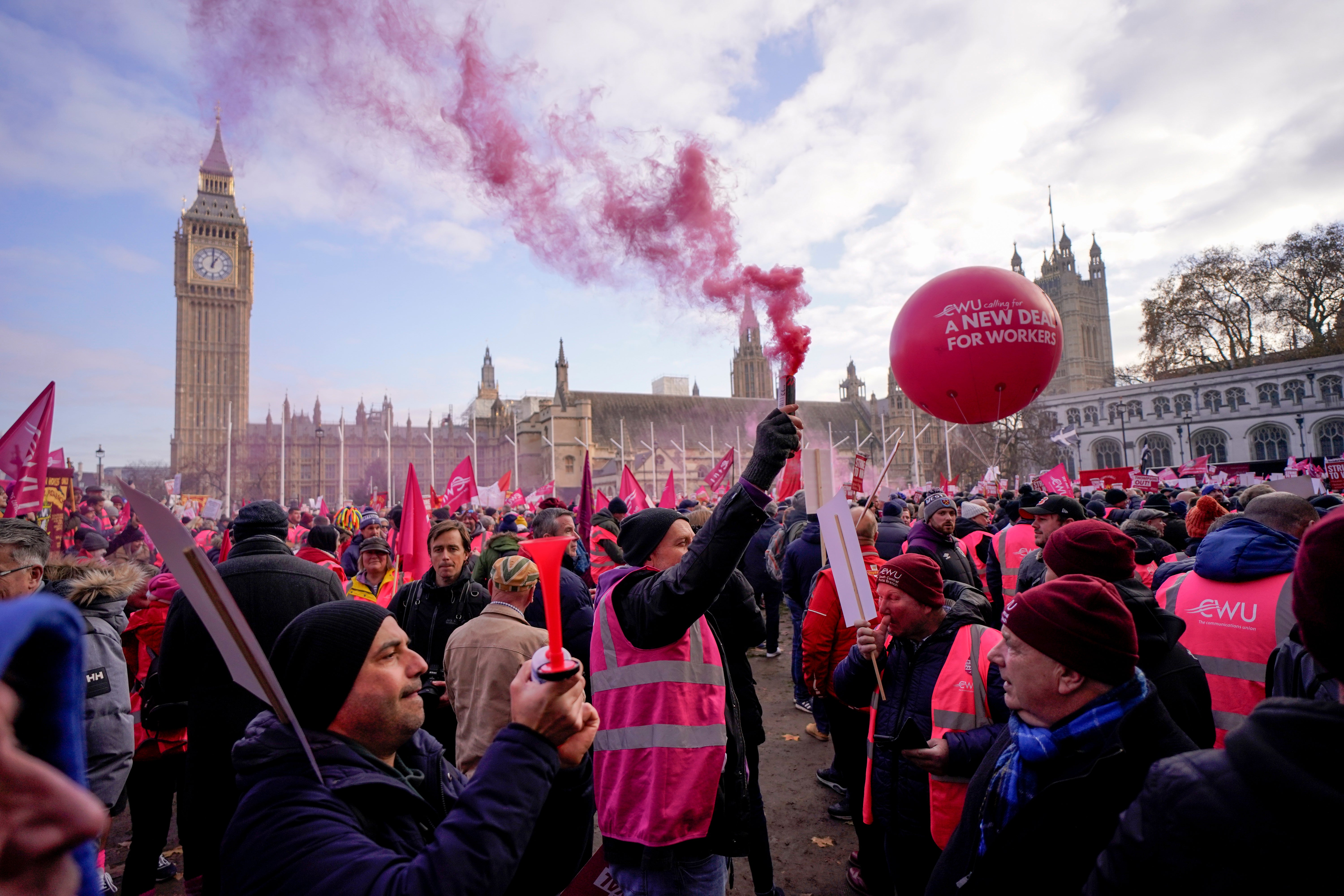 A large crowd holding signs and chanting slogans gathers in the UK