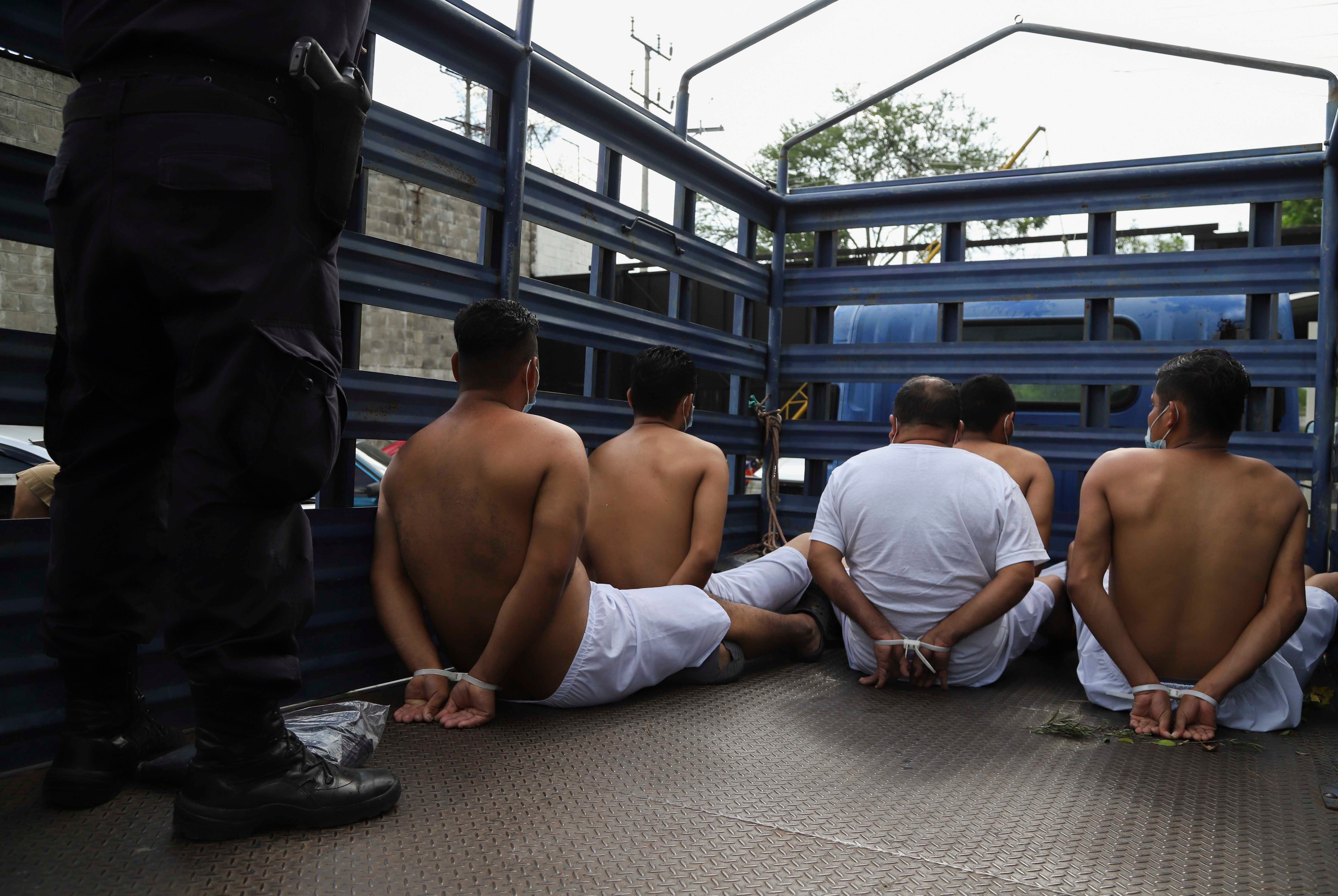 People arrested by police wait in zip tie handcuffs in the back of a truck to be transferred to a prison at the Police Delegation of San Bartolo in Soyapango, El Salvador, Tuesday, Aug. 16, 2022.
