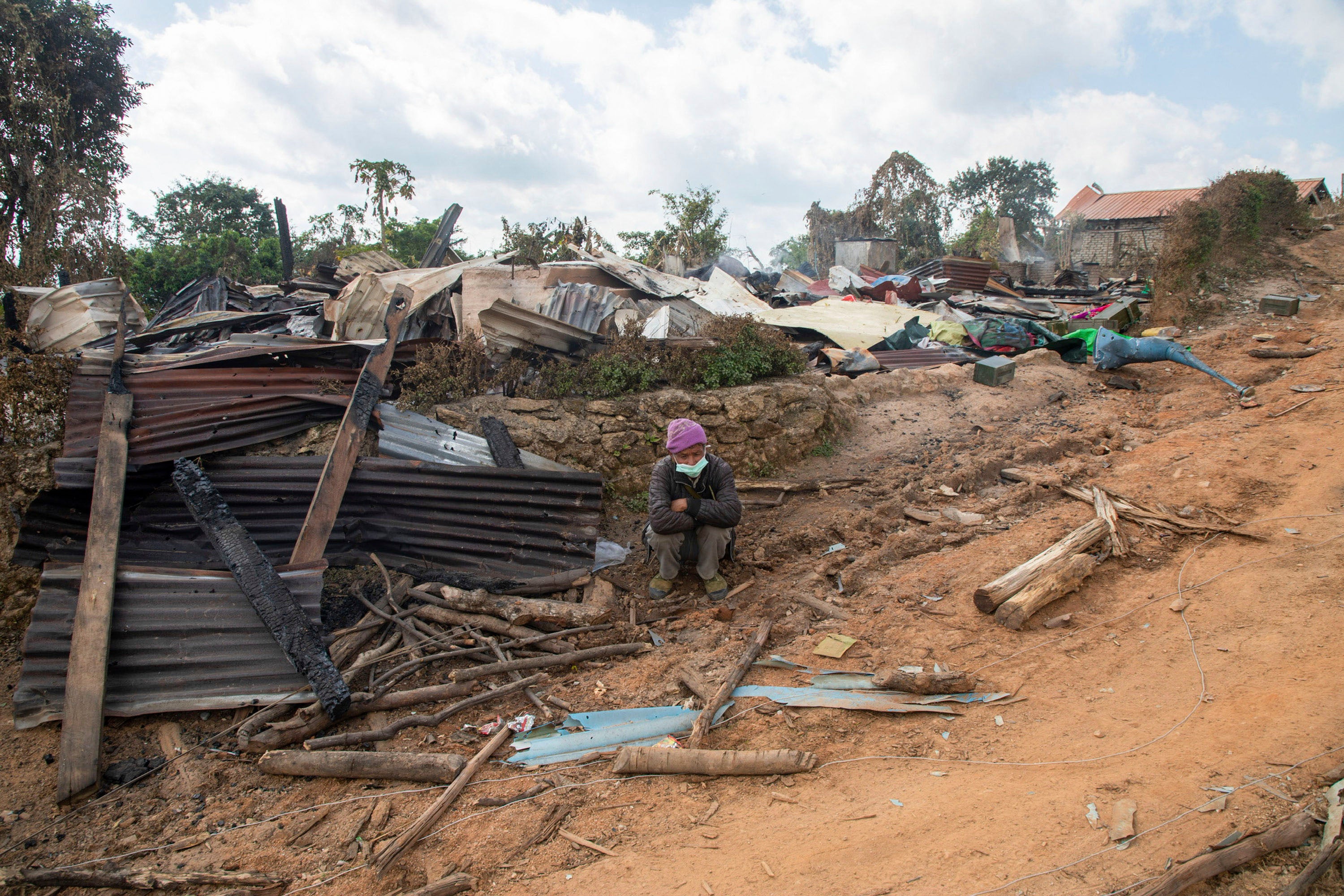 A man sits in front of a house in Shan State that was destroyed during fighting between Myanmar security forces and the Ta'ang National Liberation Army, January 10, 2023. 