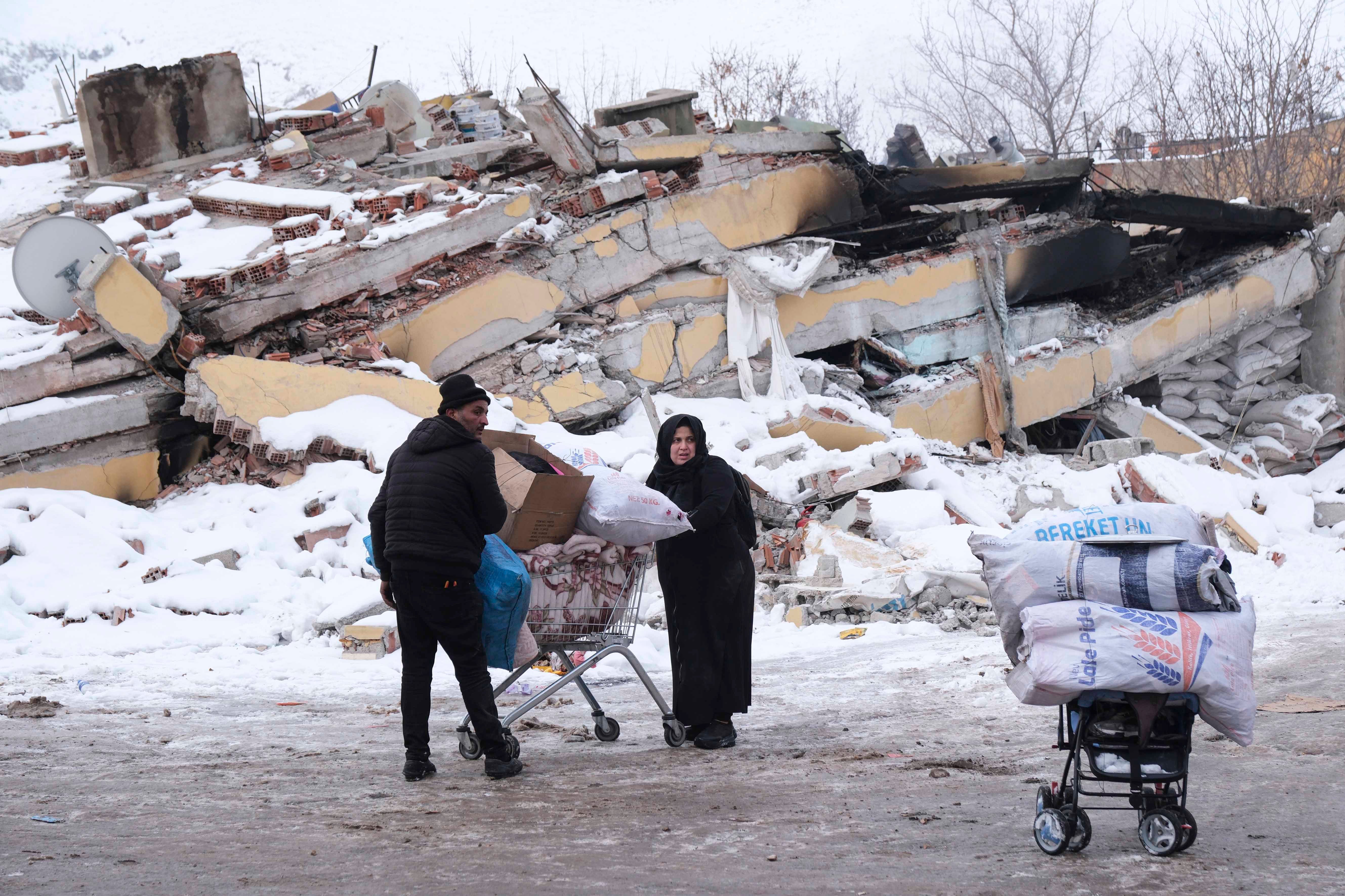 A Syrian refugee couple carry their belongings by shopping cart in Elbistan, Kahramanmaraş province, Turkey, February 8, 2023