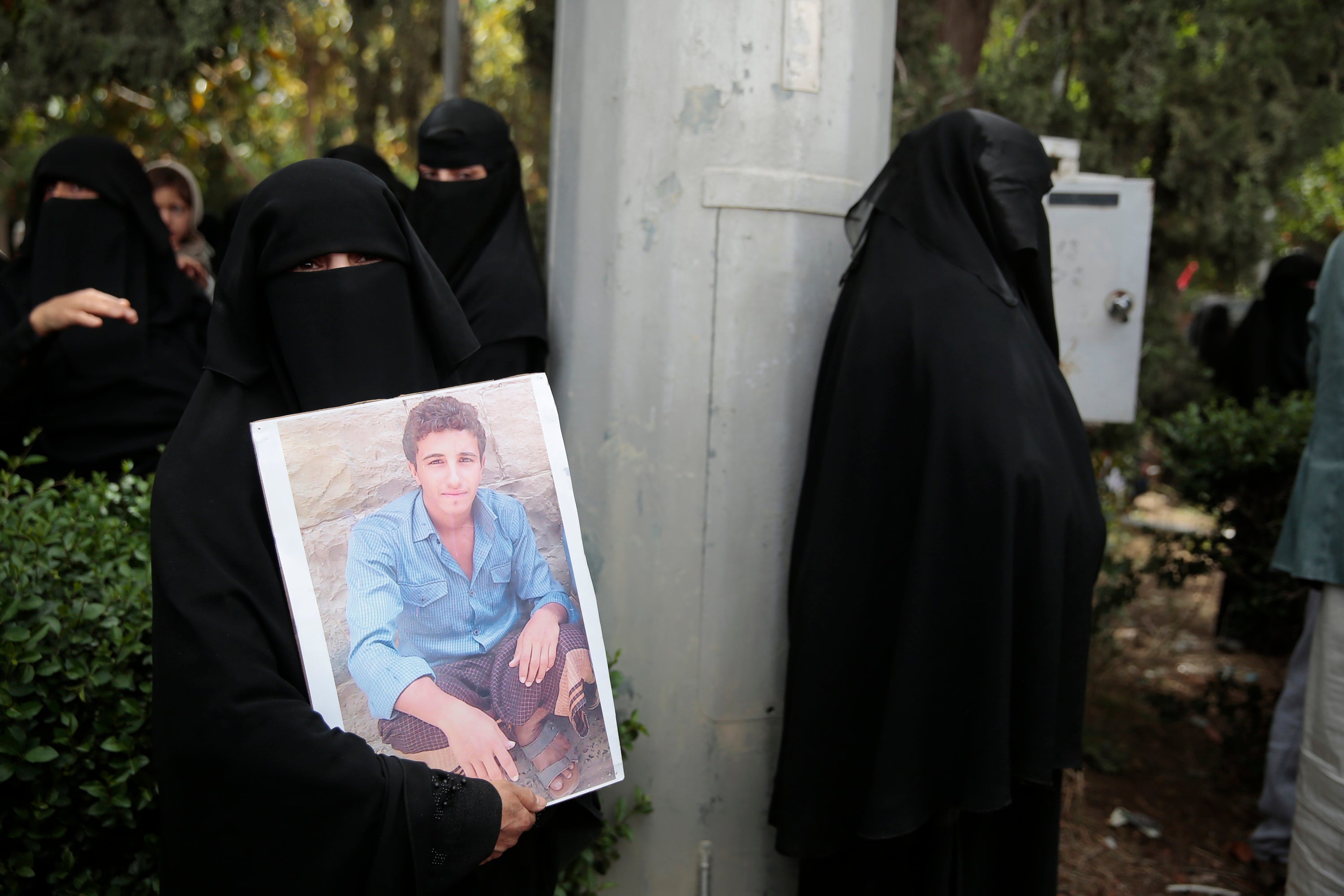 A woman holds her son's picture as she waits for Houthi prisoners to arrive at Sanaa airport, Yemen.