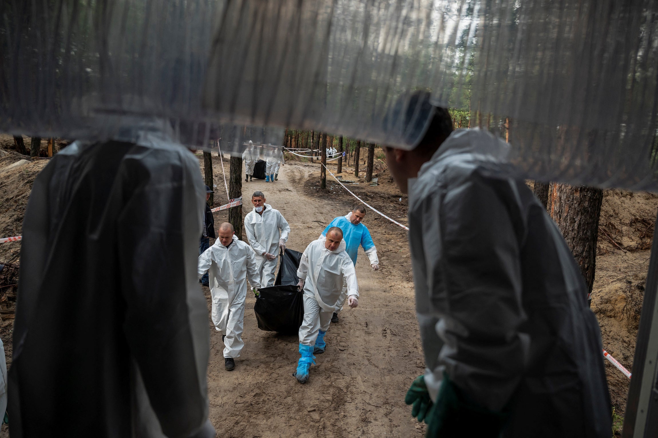 Carrying an exhumed body at a mass burial site, Izium, Ukraine, September 23, 2022.
