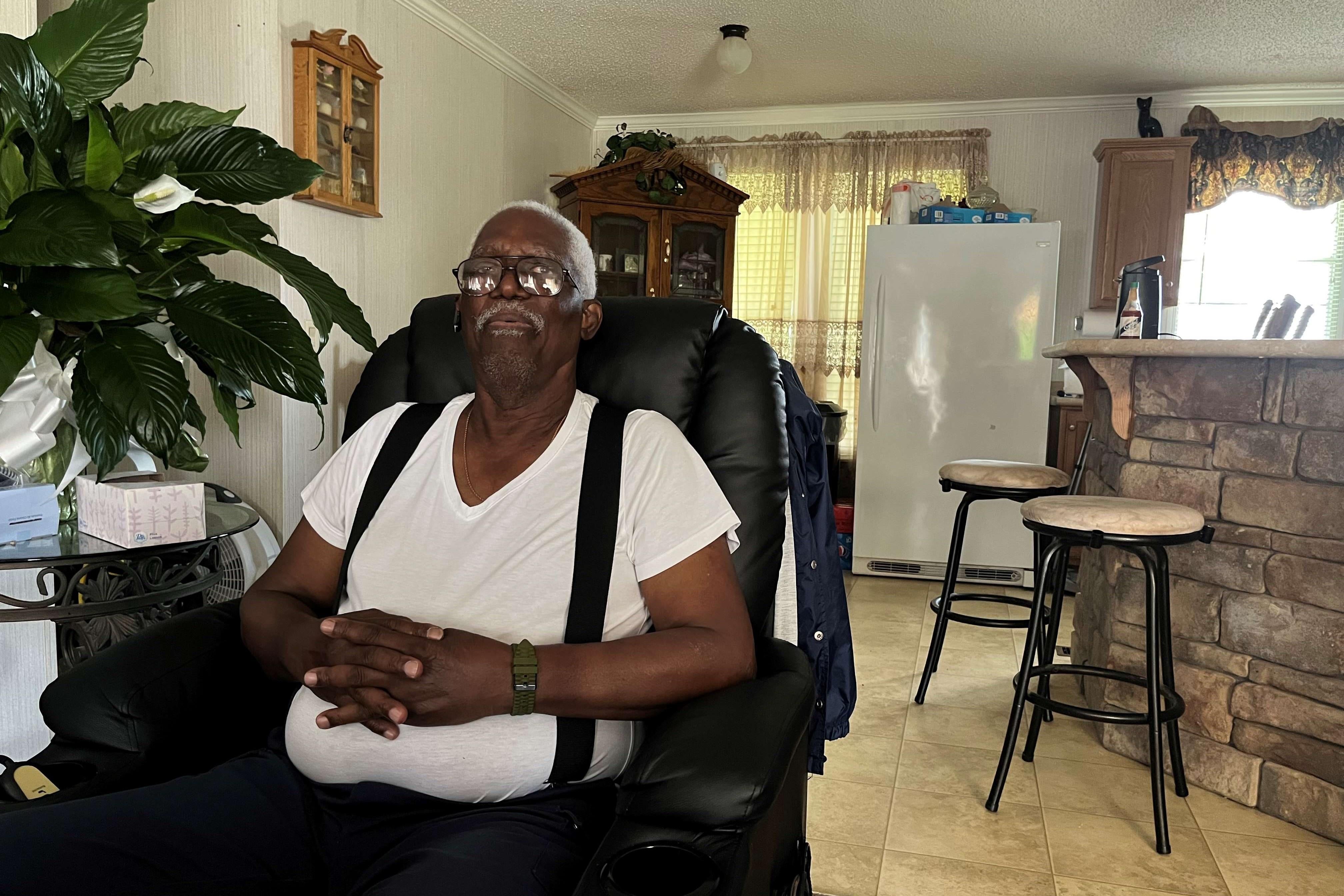 An older man poses for a photo in a chair