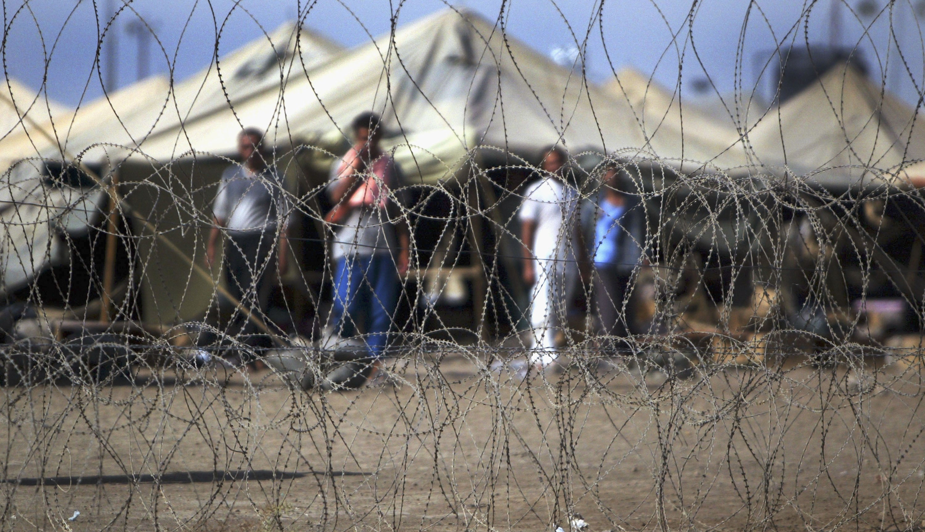 Prisoners stand next to the tents in which they are housed at the Abu Ghraib prison west of Baghdad, Iraq, July 15, 2004.