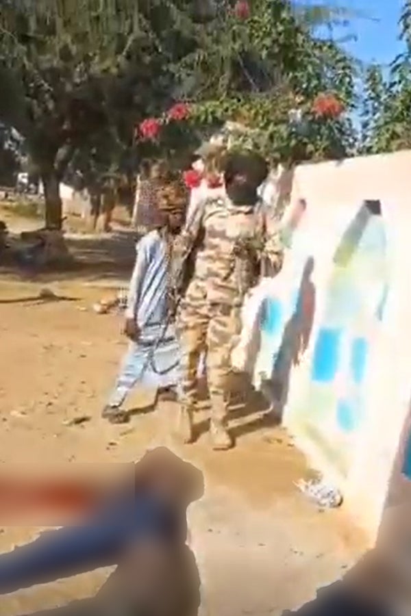 Blurred screengrab of two armed men standing over dead bodies