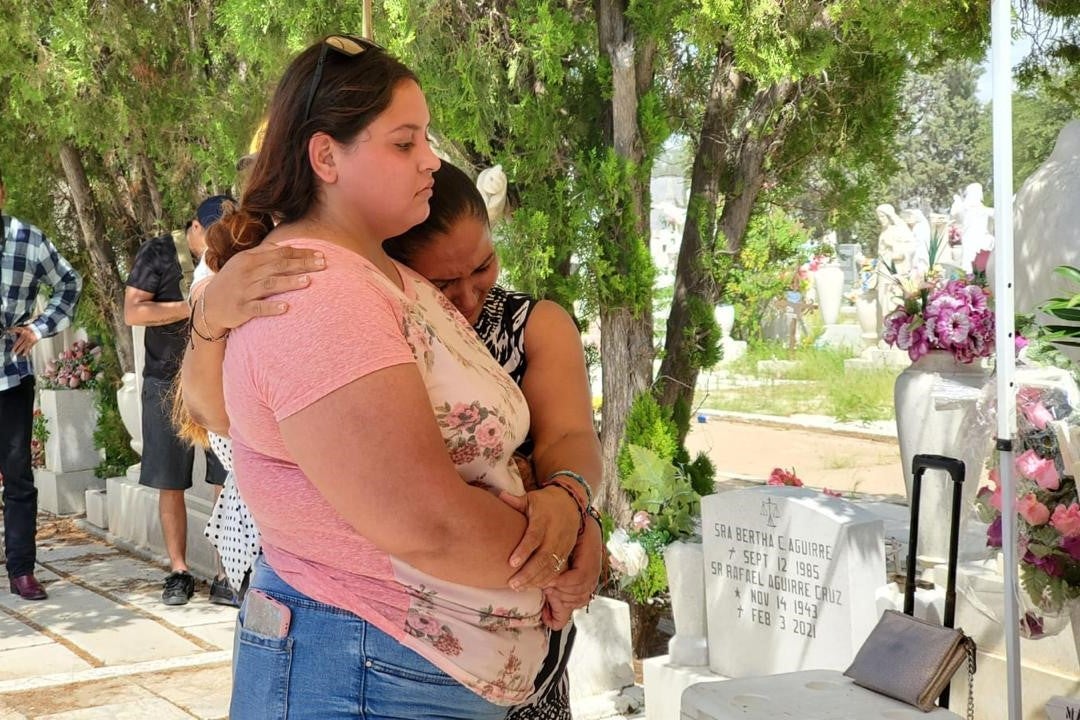 Two women embrace at a cemetery