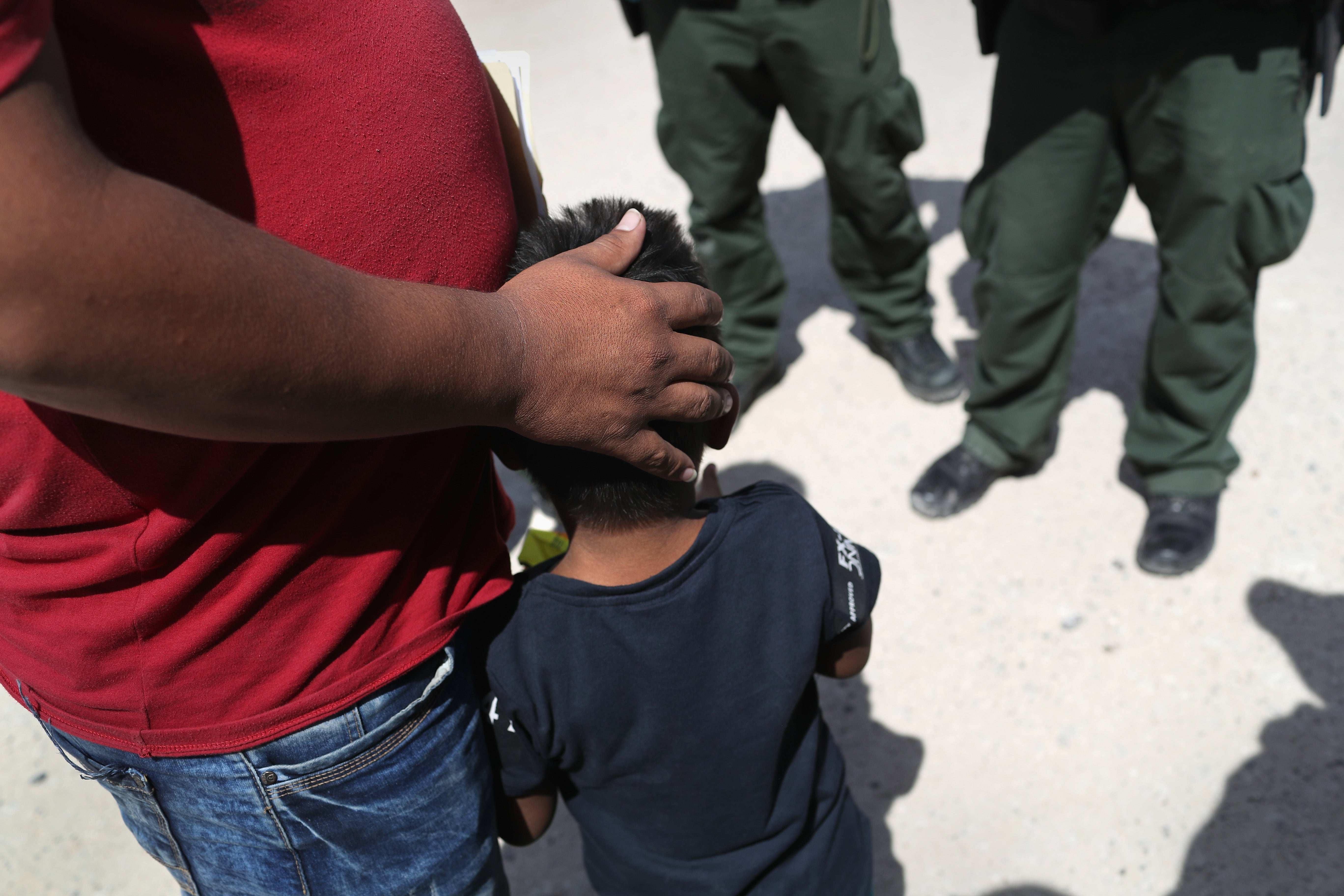 A father embraces his son in front of border agents