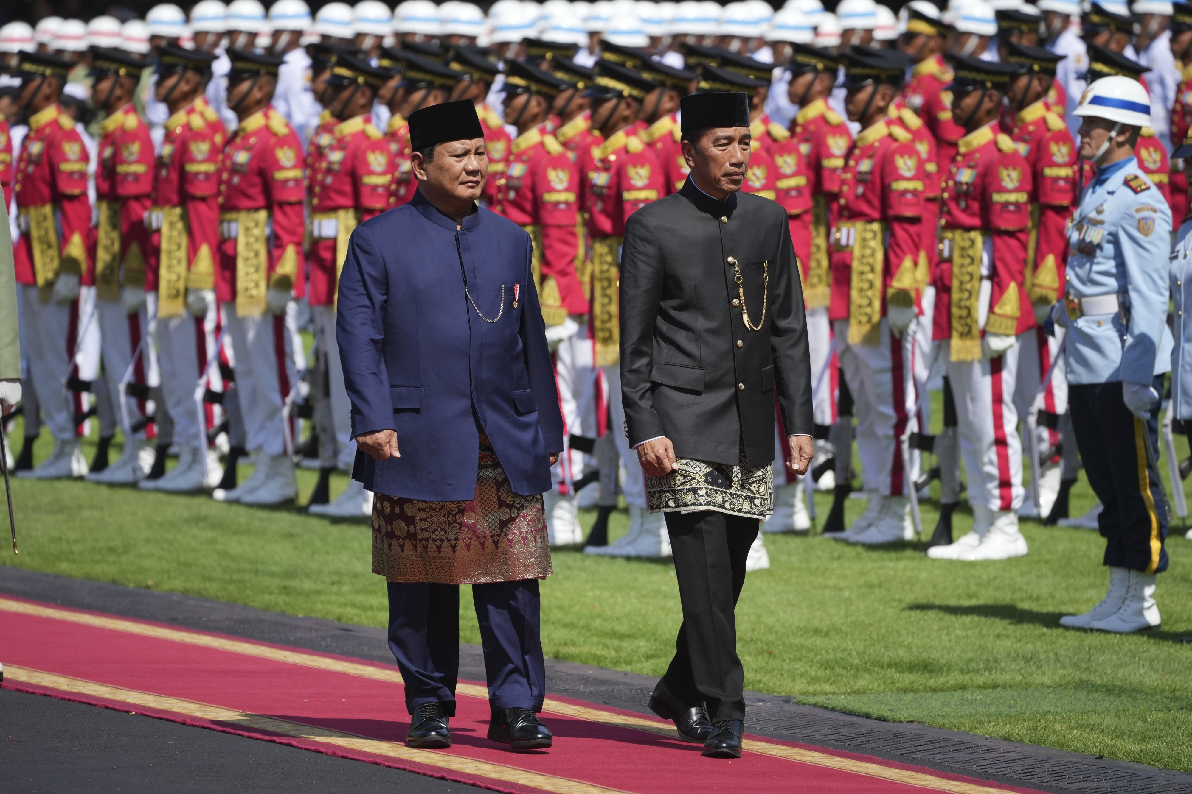 Indonesia's newly inaugurated president, Prabowo Subianto, left, and his predecessor, Joko Widodo, inspect honor guards during their handover ceremony at Merdeka Palace in Jakarta, Indonesia, October 20, 2024.