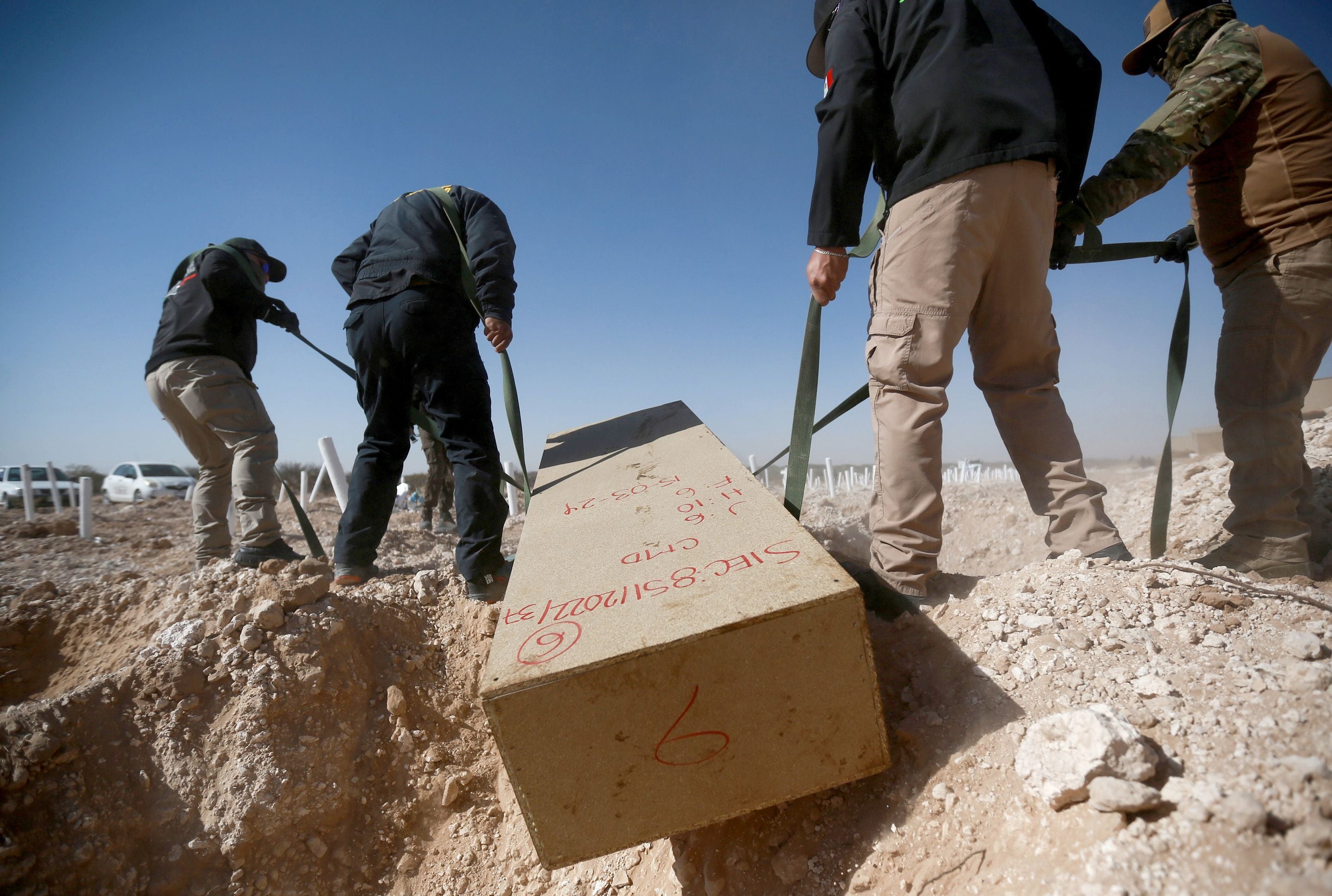 Officials from the forensic medical service place unidentified bodies in a mass grave