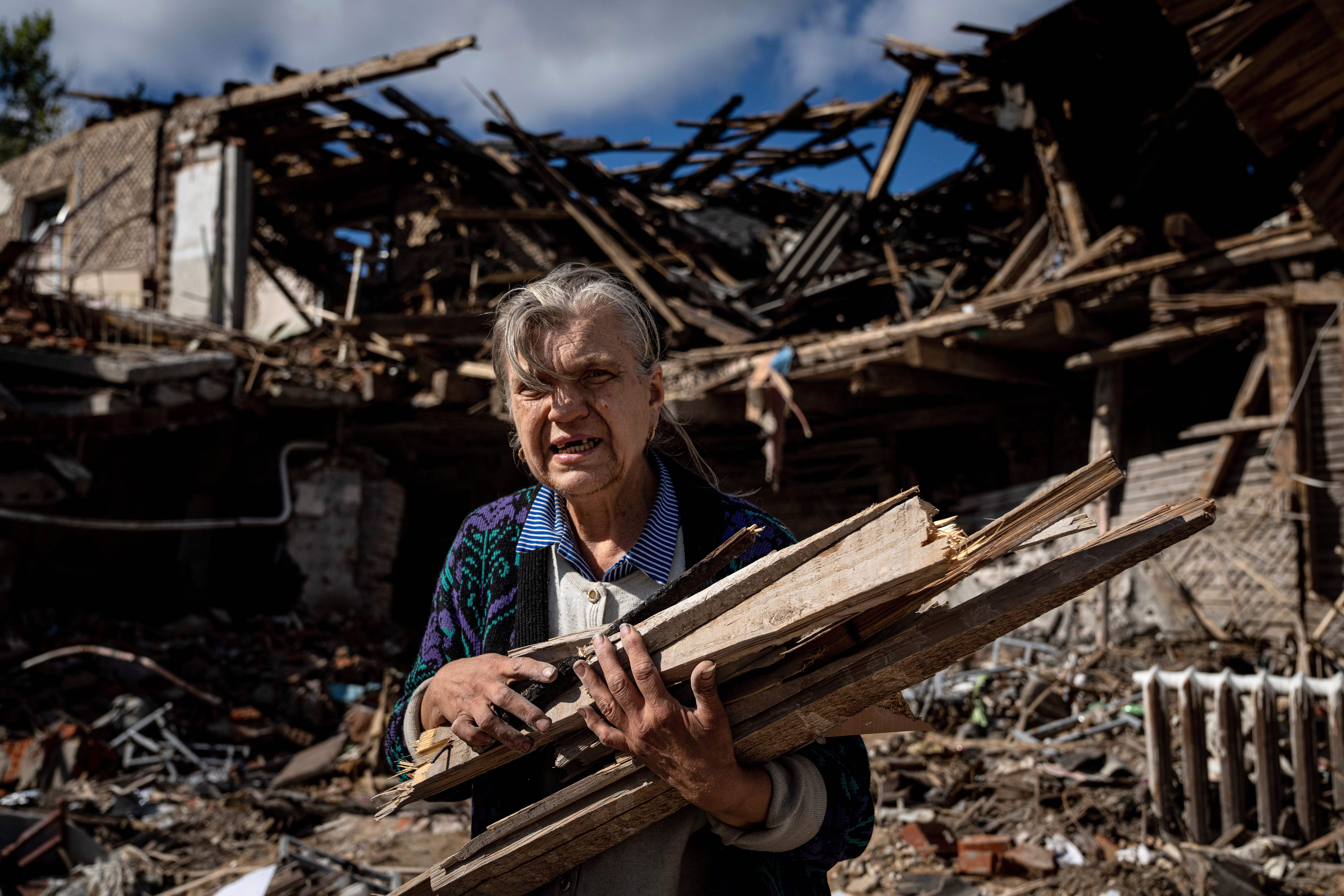 A woman collects wood for heating from a destroyed school where Russian forces were based in Izium, Ukraine, September 19, 2022. 
