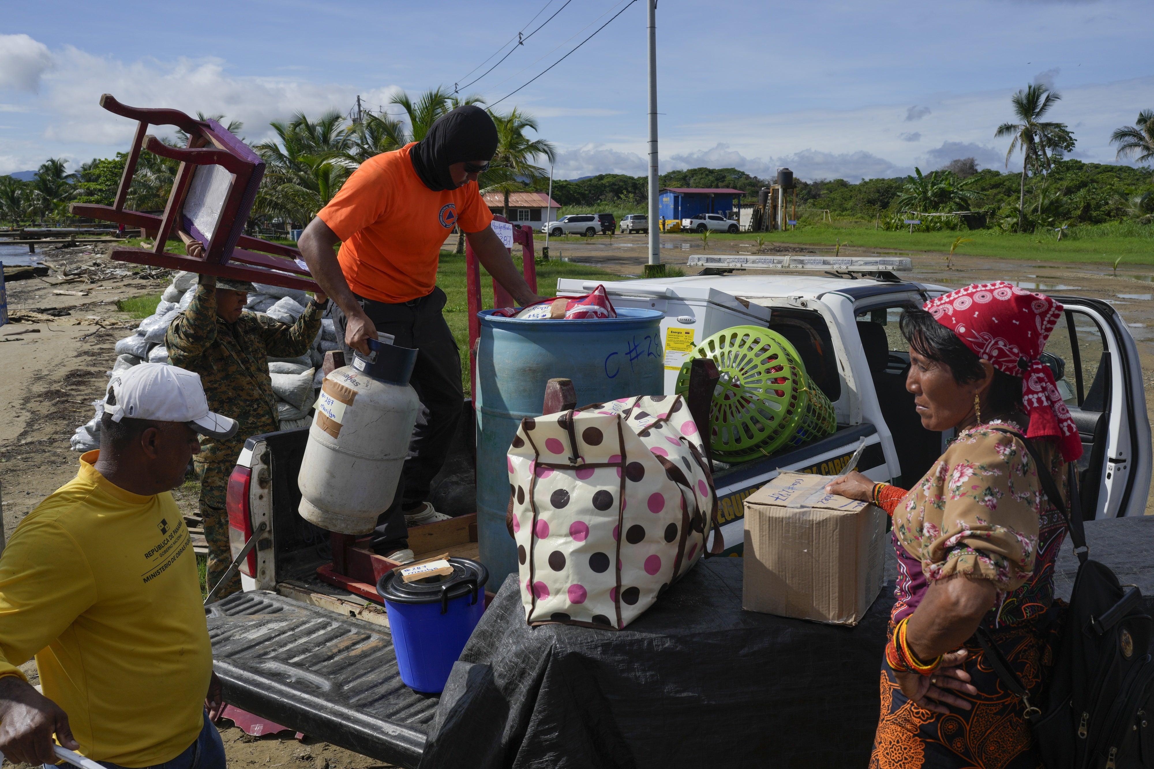 Civil protection officials, left, load a family's belongings on a truck to move from the island of Gardi Sugdub, located off Panama's Caribbean coast, to Nuevo Carti on the mainland, June 5, 2024.