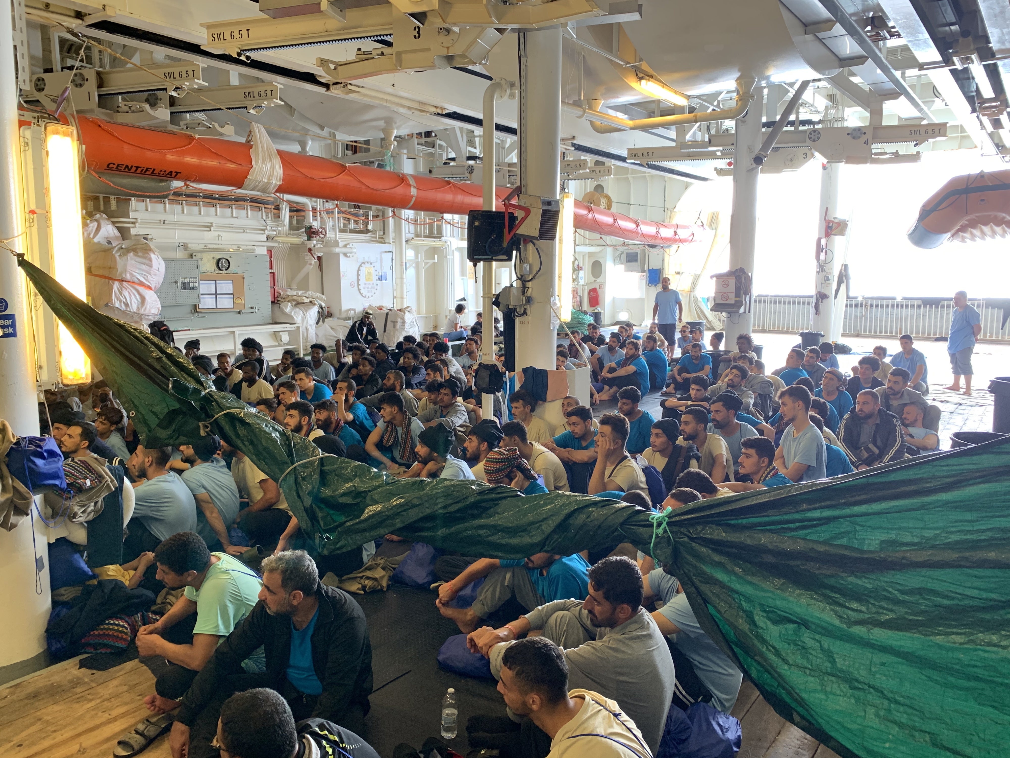 Des rescapés assis sur le « pont-abri » du Geo Barents écoutaient les informations délivrées par l’équipe de MSF, le 20 septembre 2024.