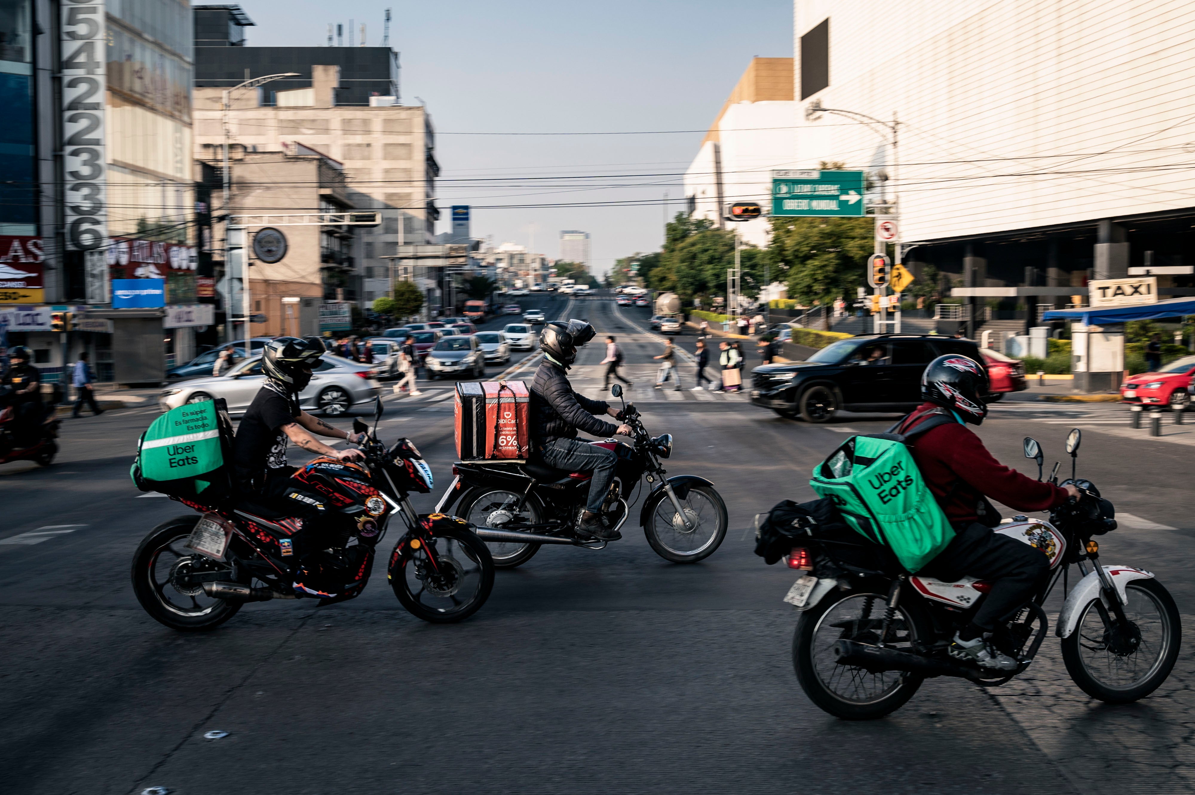 Delivery workers carry Uber Eats and Didi bags in Mexico City, Mexico, on December 12, 2024. 