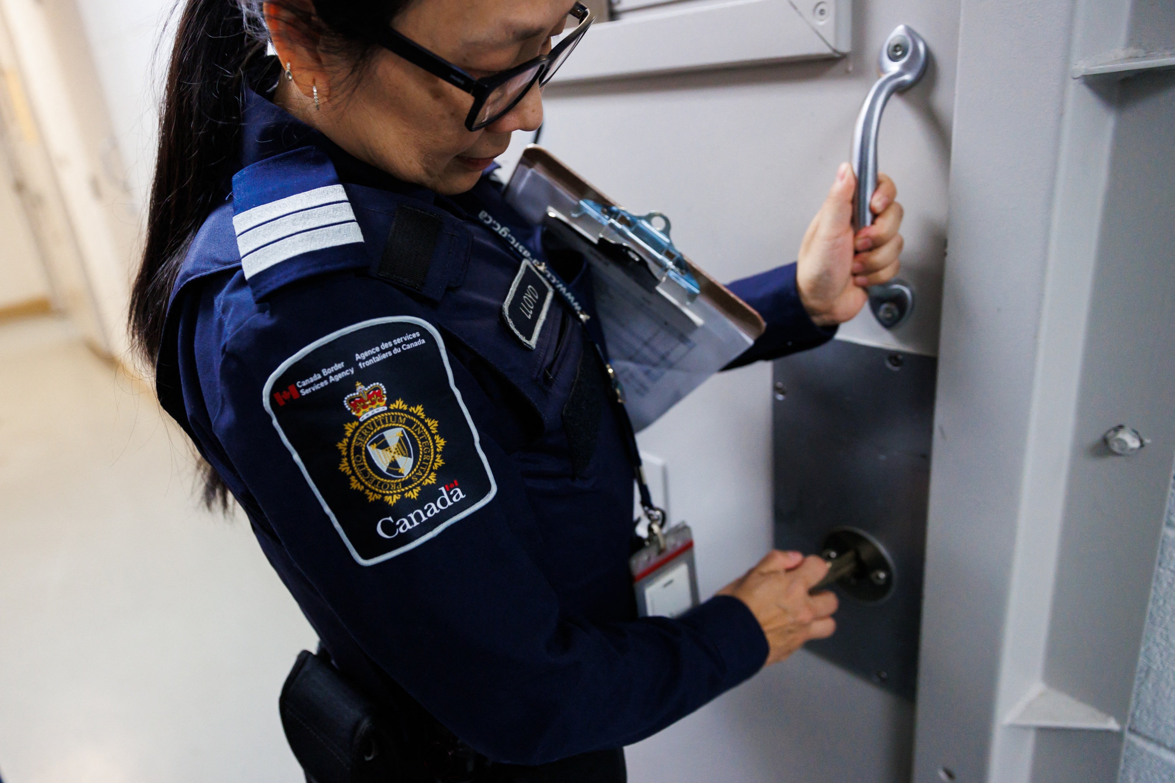 An officer demonstrates locking the door of a wet cell at the Toronto Immigration Holding Centre