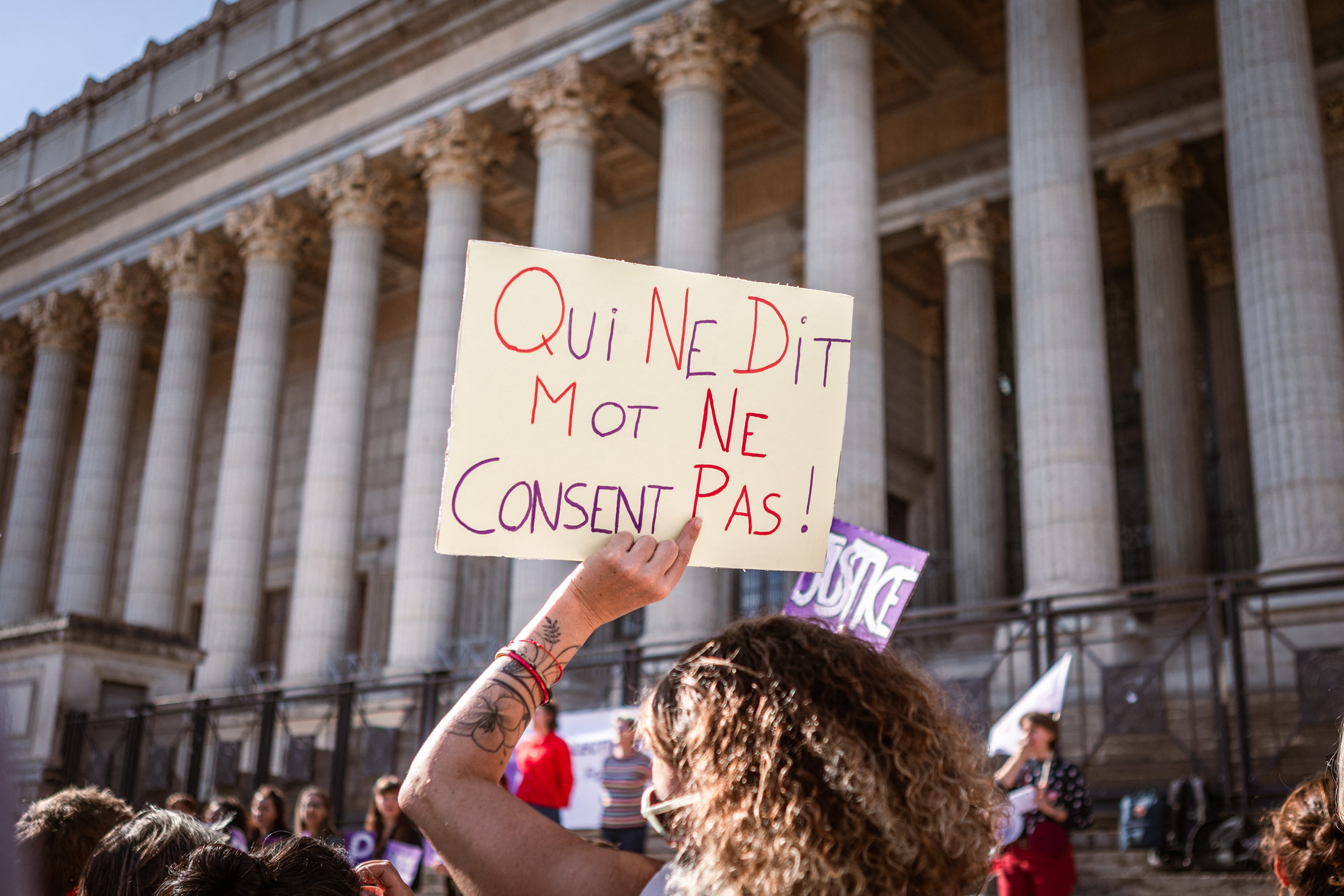 Une personne brandissant une pancarte sur laquelle on peut lire « Qui ne dit mot ne consent pas » devant le Palais de Justice lors d'un rassemblement en soutien à toutes les victimes de violences sexuelles et sexistes à Lyon, France, le 19 octobre 2024. 