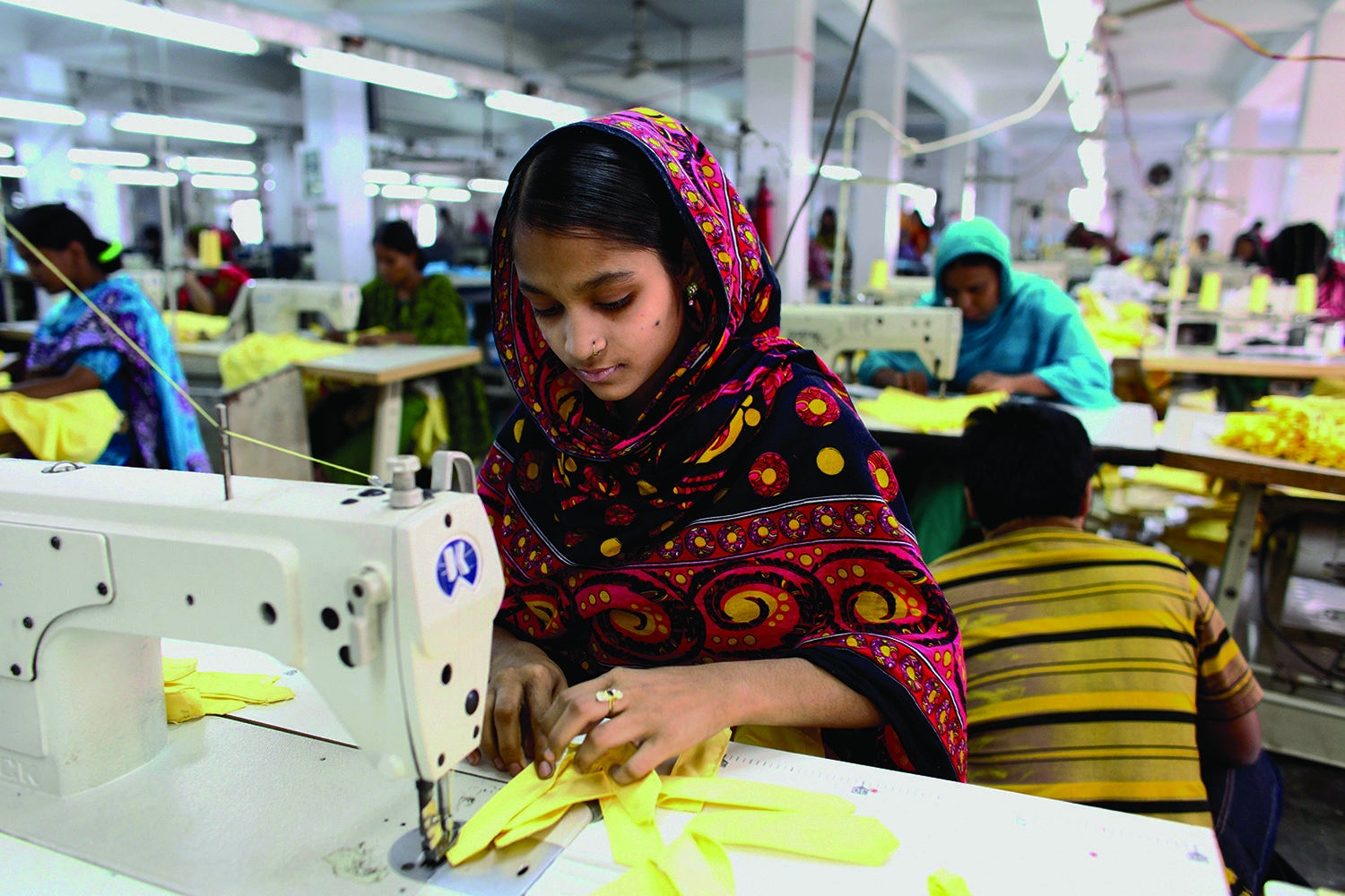 A garment worker sews clothing in a building near the site of the Rana Plaza building collapse. 