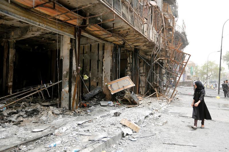 A girl walks past the site after a suicide car bomb attack at the shopping area of Karrada, a largely Shi'ite district, in Baghdad, Iraq July 4, 2016. 