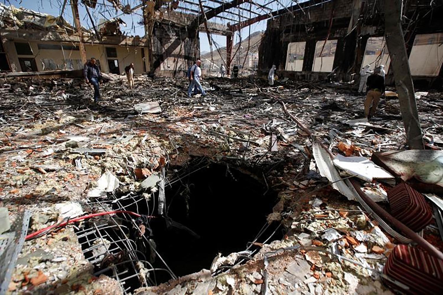 Journalists and police inspect the scene at the community hall in Sanaa that Saudi-led coalition warplanes attacked on October 8, 2016. 