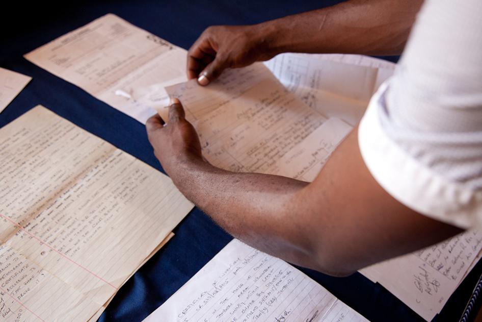 "Adam," arrested in Kenya in February 2015 on homosexuality charges and subjected to a forced anal exam, sorts through police documents on his case. © 2015 Zoe Flood