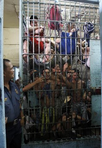 A policeman looks on at prisoners crowded into a detention cell in Manila, Philippines on May 13, 2011. 