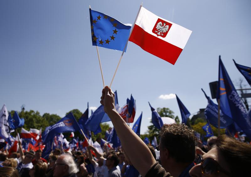 People wave EU and Polish flags as they march during anti-government demonstration organized by main opposition parties in Warsaw, Poland May 7, 2016.