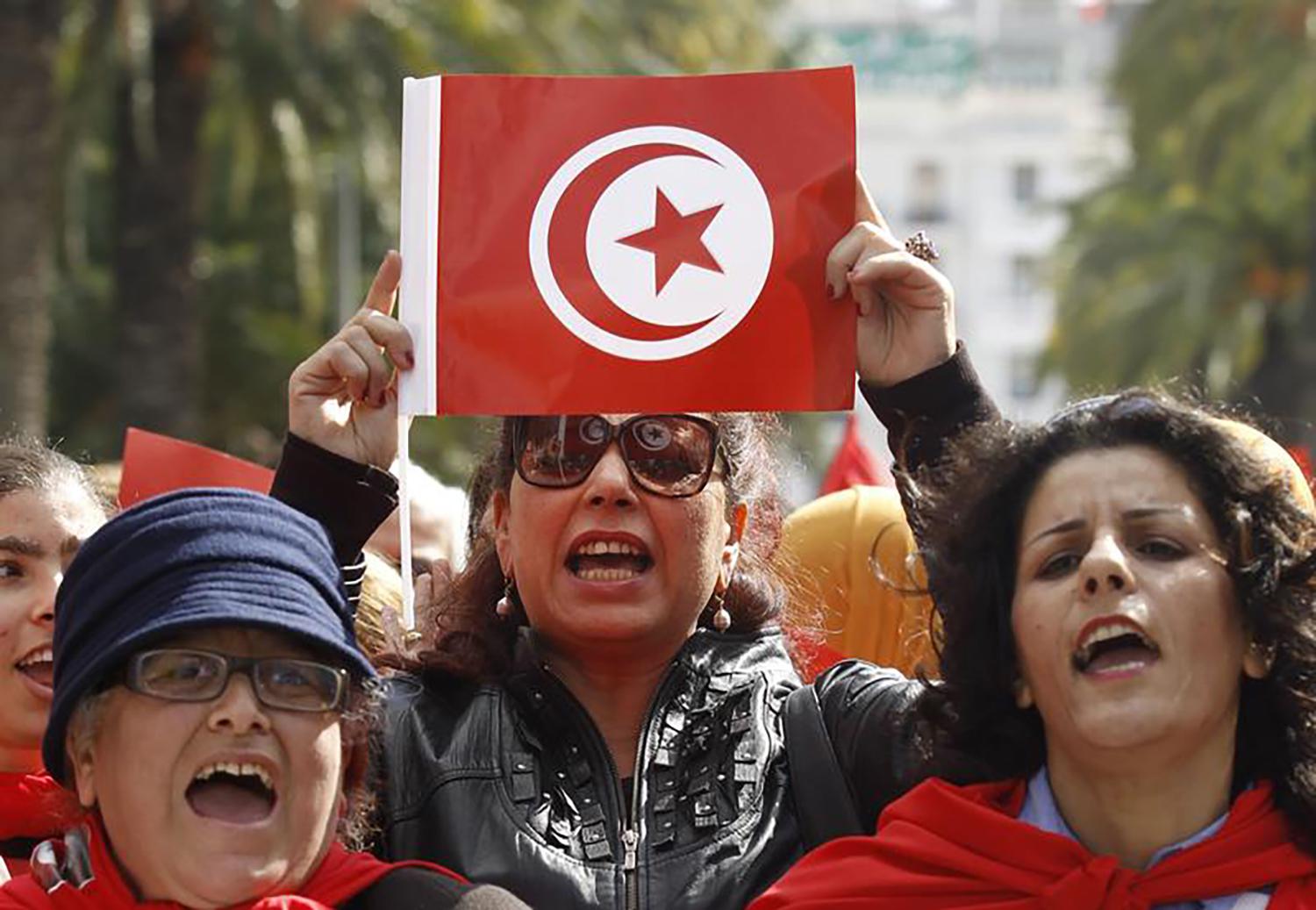 Une femme tunisienne tient un drapeau, lors d’un rassemblement tenu à Tunis à l’occasion de la Journée internationale de la femme, le 8 mars 2014.
