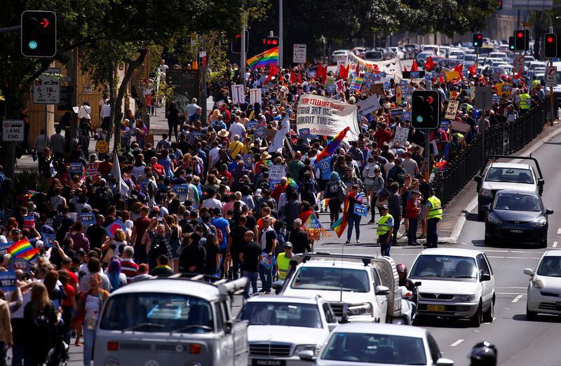 Police watch marchers holding signs and banners as they participate in a marriage equality march in central Sydney, Australia.