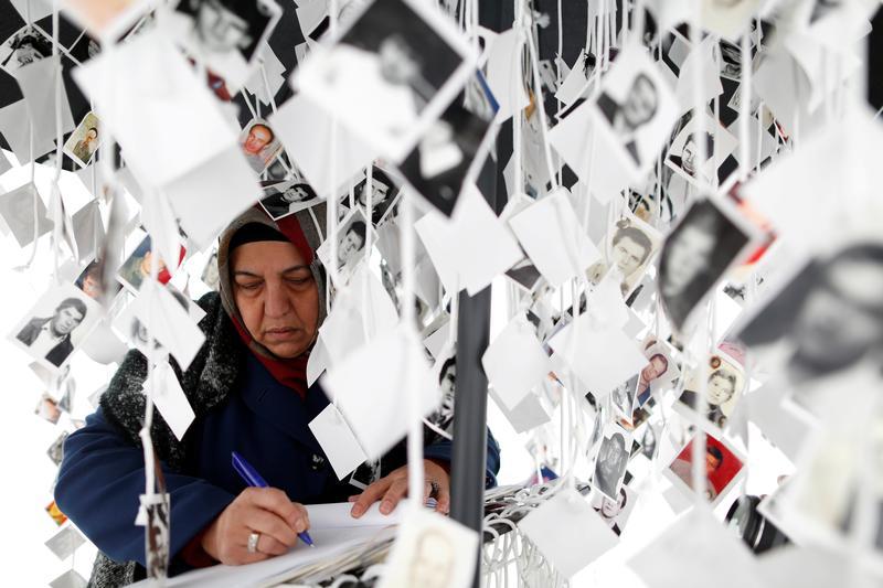 A woman writes in a book inside a traveling monument called 'Prijedor 92' outside the Yugoslav War Crimes Tribunal (ICTY)