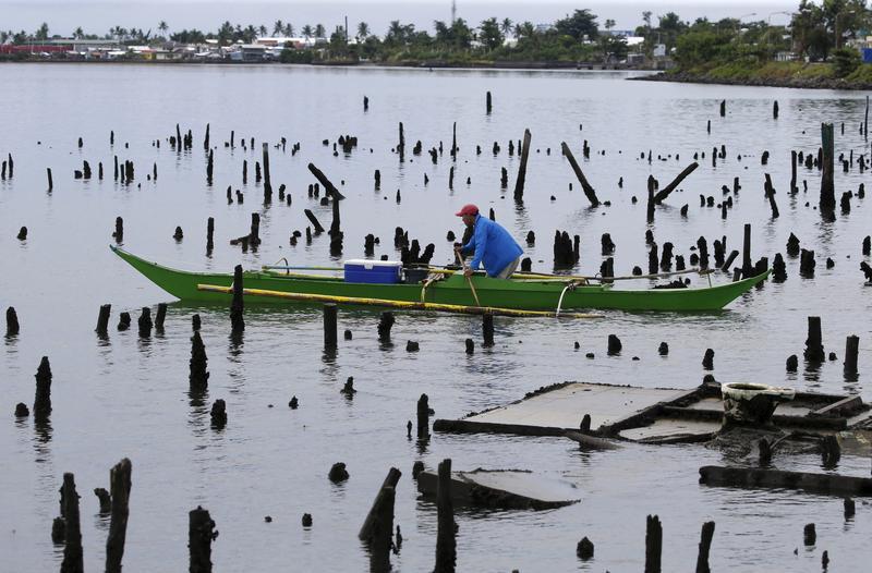 A fisherman paddles his banca amidst ruins of house stilts destroyed by Typhoon Haiyan on a coastal village in Tacloban city in central Philippines November 2, 2015.