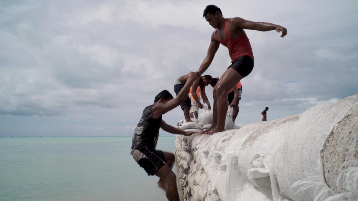 Men construct a seawall in Kiribati, located in the Pacific Ocean. Kiribati’s islands may become uninhabitable as ocean levels rise due to climate change. 