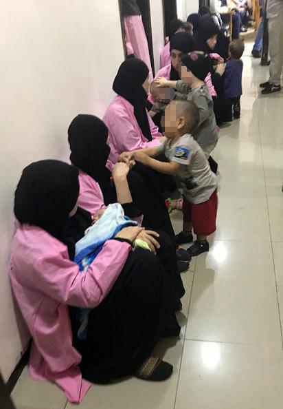 Russian women, sentenced to life in prison on grounds of joining ISIS, sit with children in a hallway of Baghdad's Central Criminal Court, April 29, 2018. © 2018 Ammar Karim/AFP/Getty Images