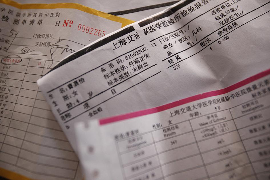 中国上海康花新村居民的血铅检测报告单，摄於2011年9月15日。上海城郊工业区里有许多这样的村落，村民指出，附近工厂和垃圾场导致家中孩童血铅超标。铅中毒的污染源一时难以查明，但该村南边有工业区，四周有玉米田、菜园和老旧农舍，多家化工、电池和电子工厂均近在咫尺。