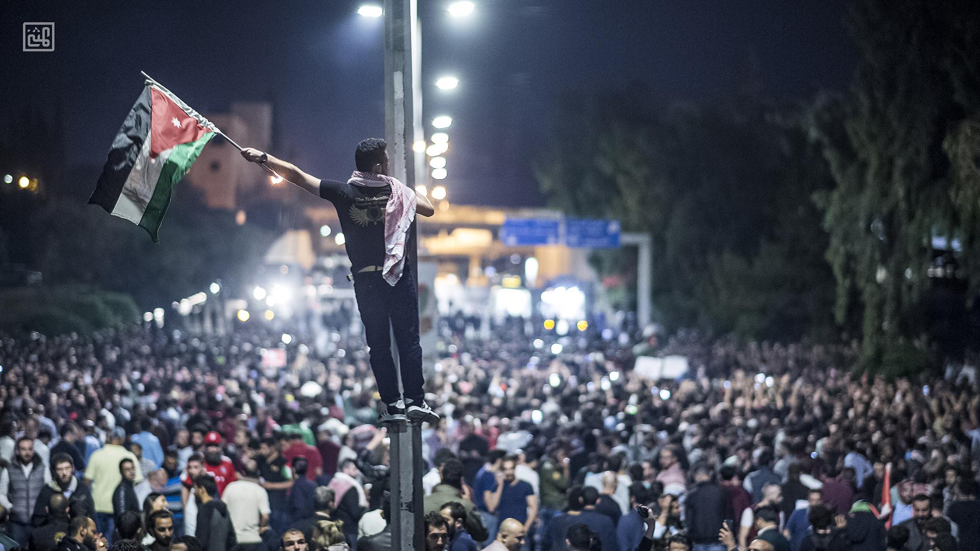 Protestor raises the Jordanian flag during 2018 protest in front of the prime ministry building in Amman
