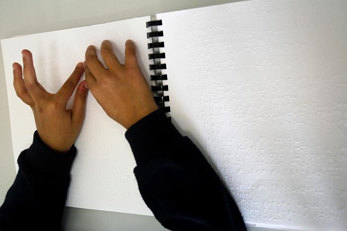 A blind girl reads from a Braille book in a classroom at the Royal Academy for the Blind in Amman.